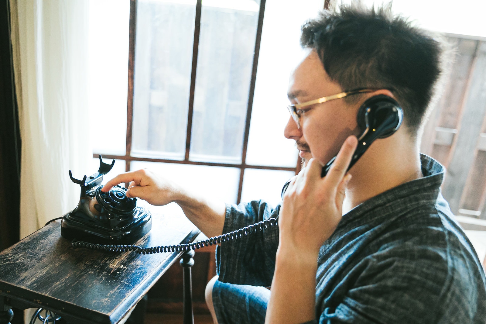 「ダイヤル式電話機を使って電話をかけるドイツ人ハーフ」の写真［モデル：Max_Ezaki］