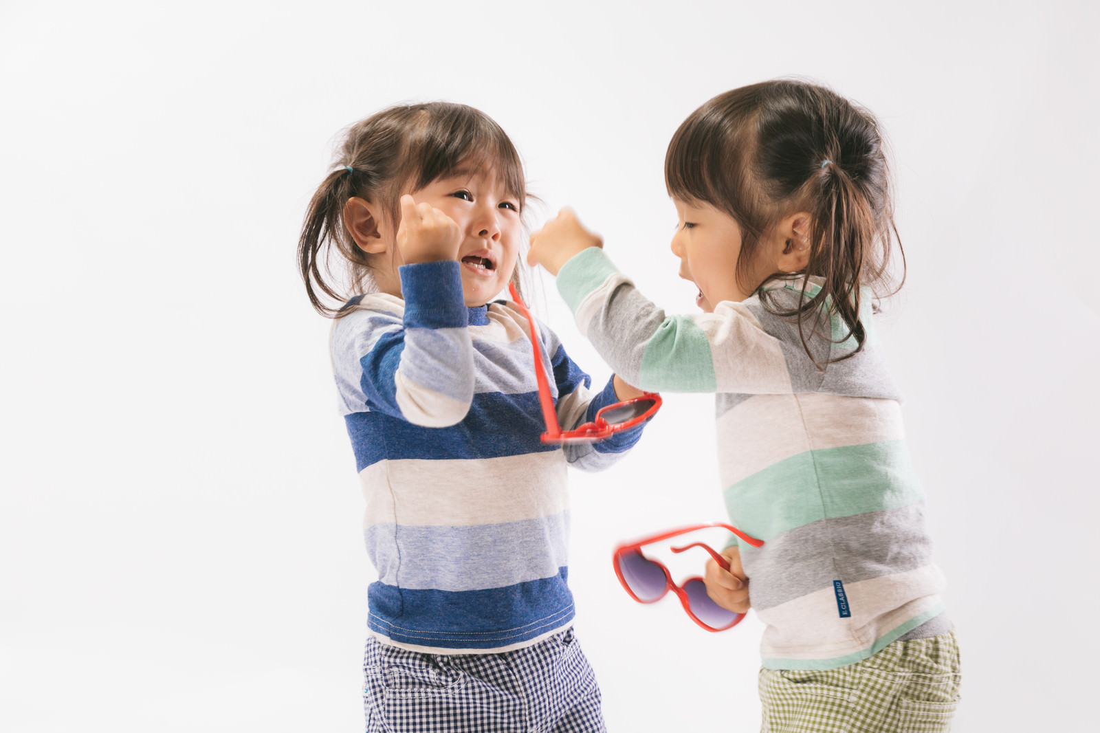 「ボカスカ取り合いの喧嘩をする双子姉妹」の写真［モデル：あおみどり］