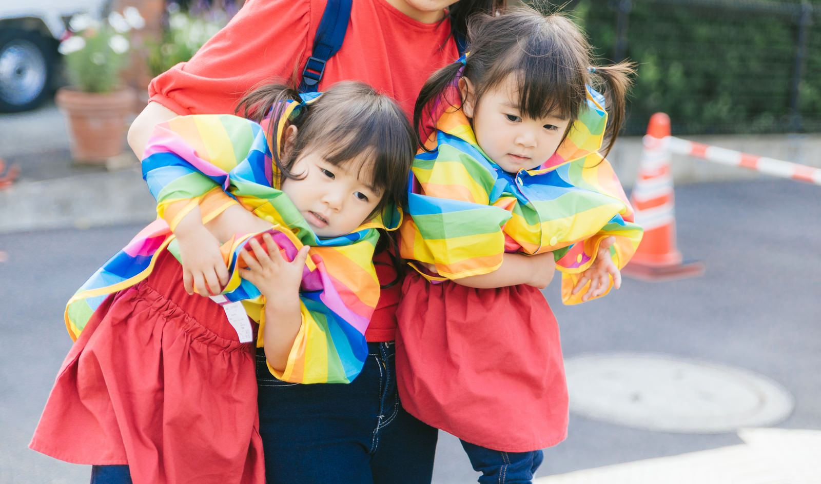 「駄々をこねる双子と抱きかかえる母親」の写真［モデル：あおみどり］