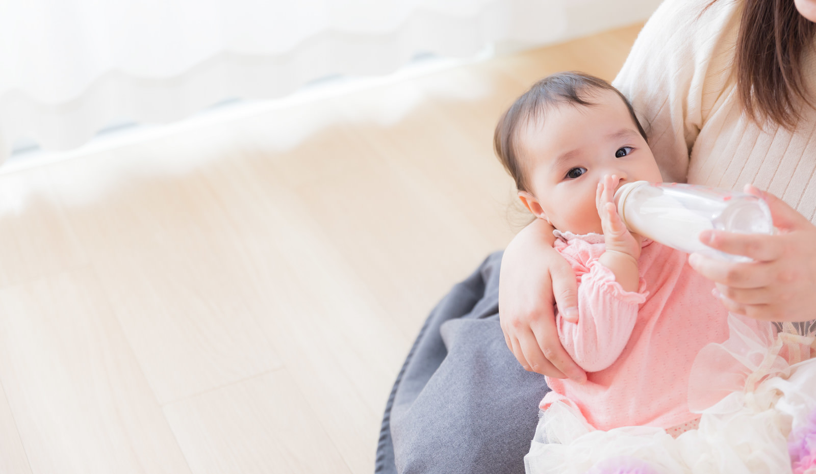 「ママに抱かれて哺乳瓶でミルクを飲む赤ちゃん」の写真［モデル：めぐな］