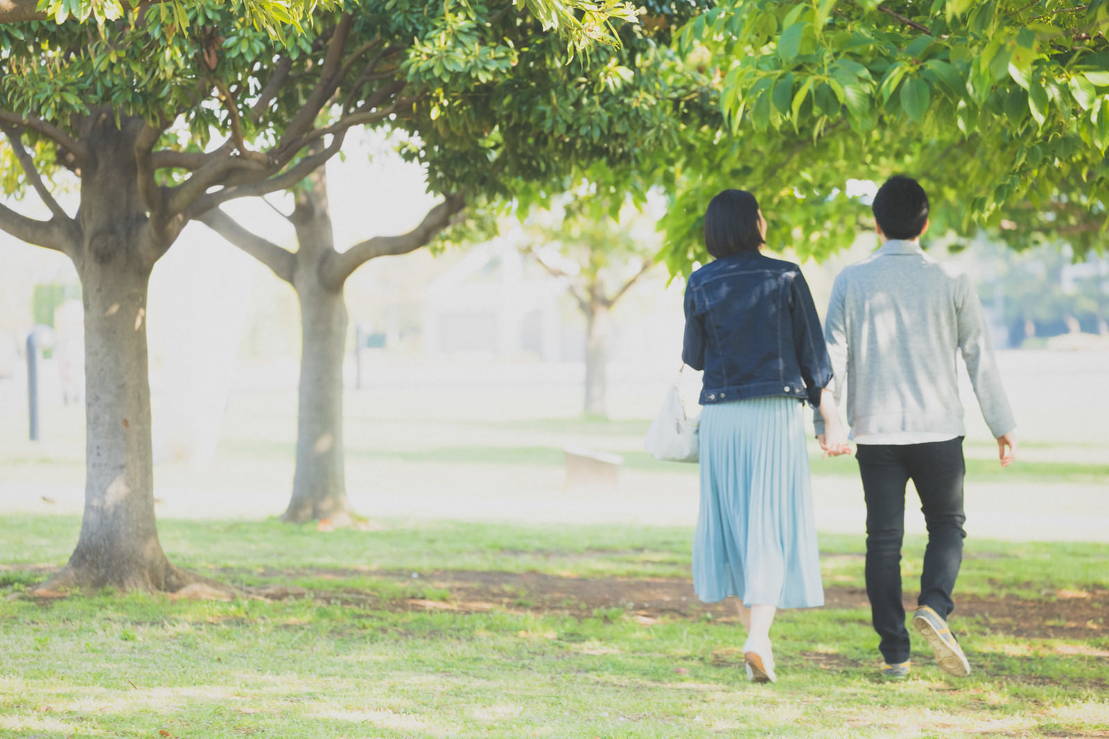 「新緑の公園を歩く男女カップル」の写真［モデル：たけべともこ］