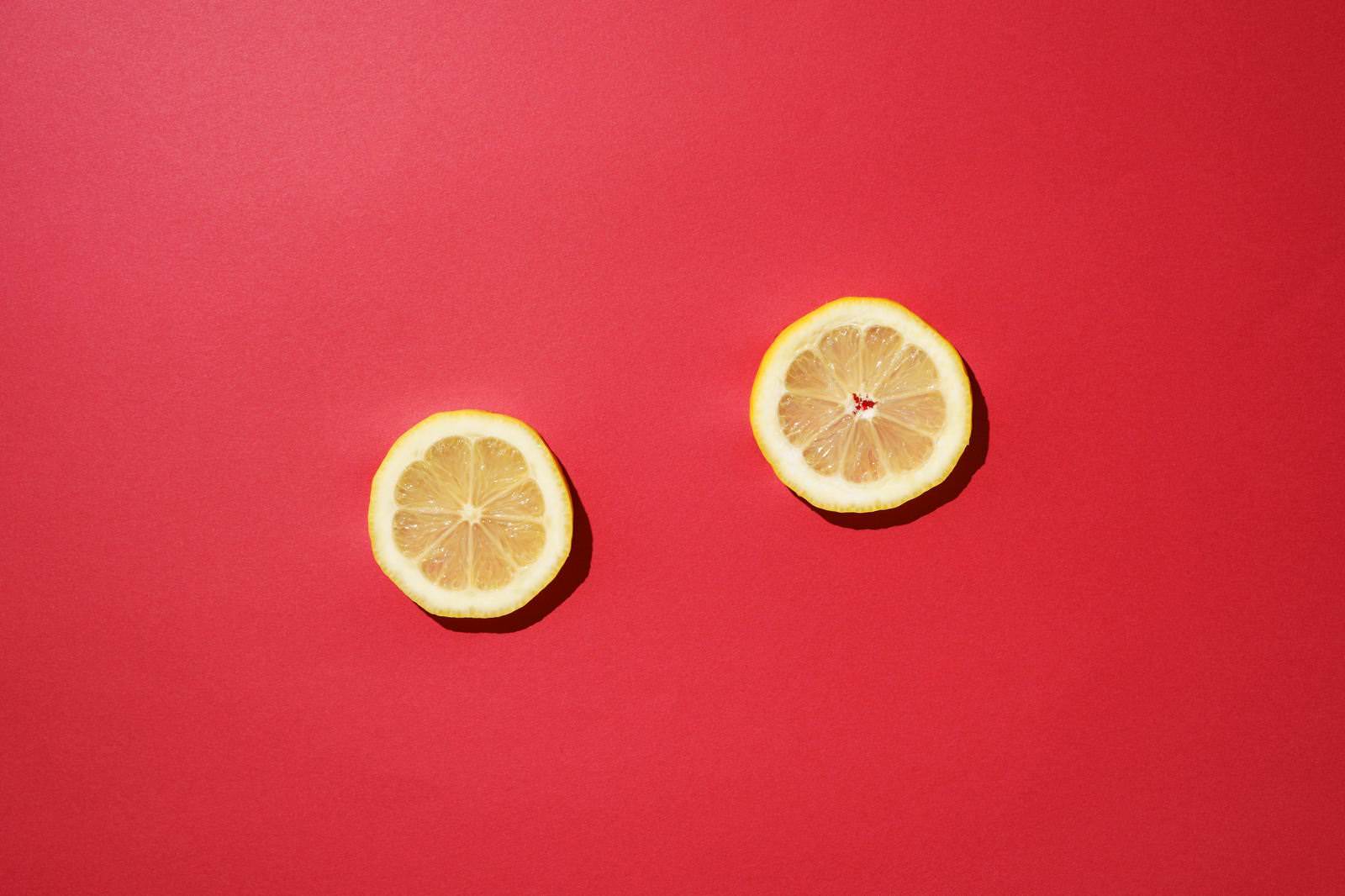 「赤い背景とレモンの輪切り | フリー素材のぱくたそ」の写真