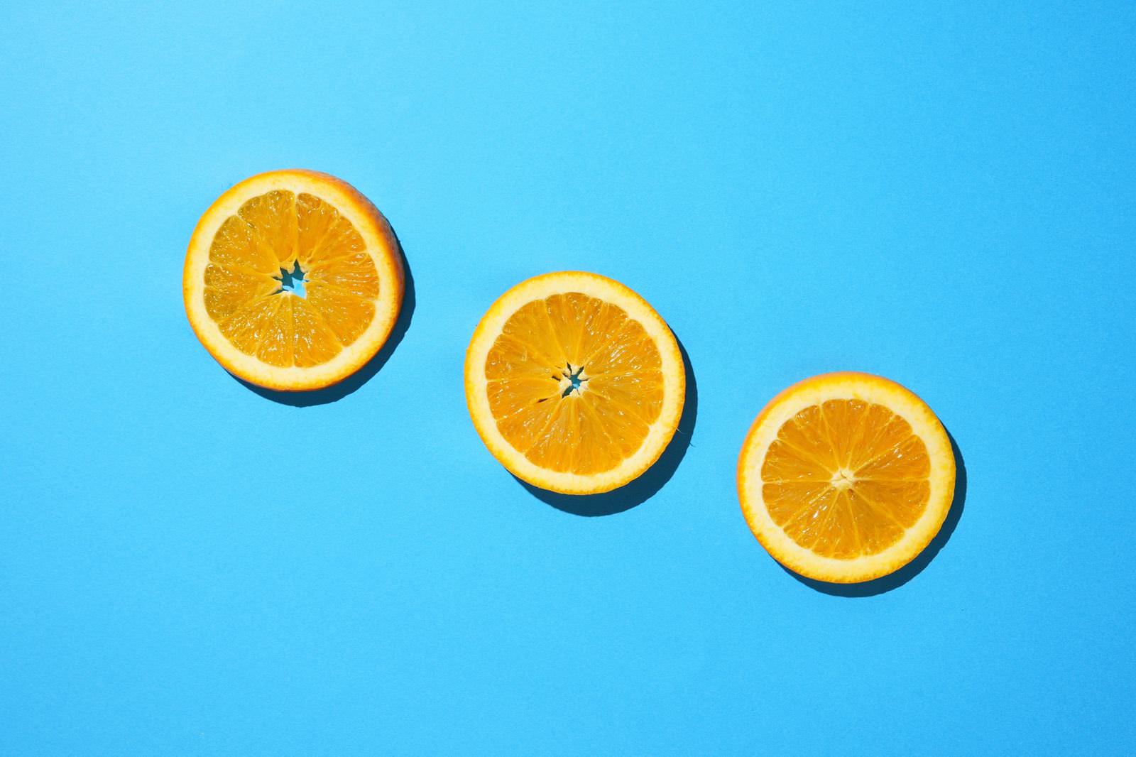 「青色の背景と輪切りオレンジ | フリー素材のぱくたそ」の写真