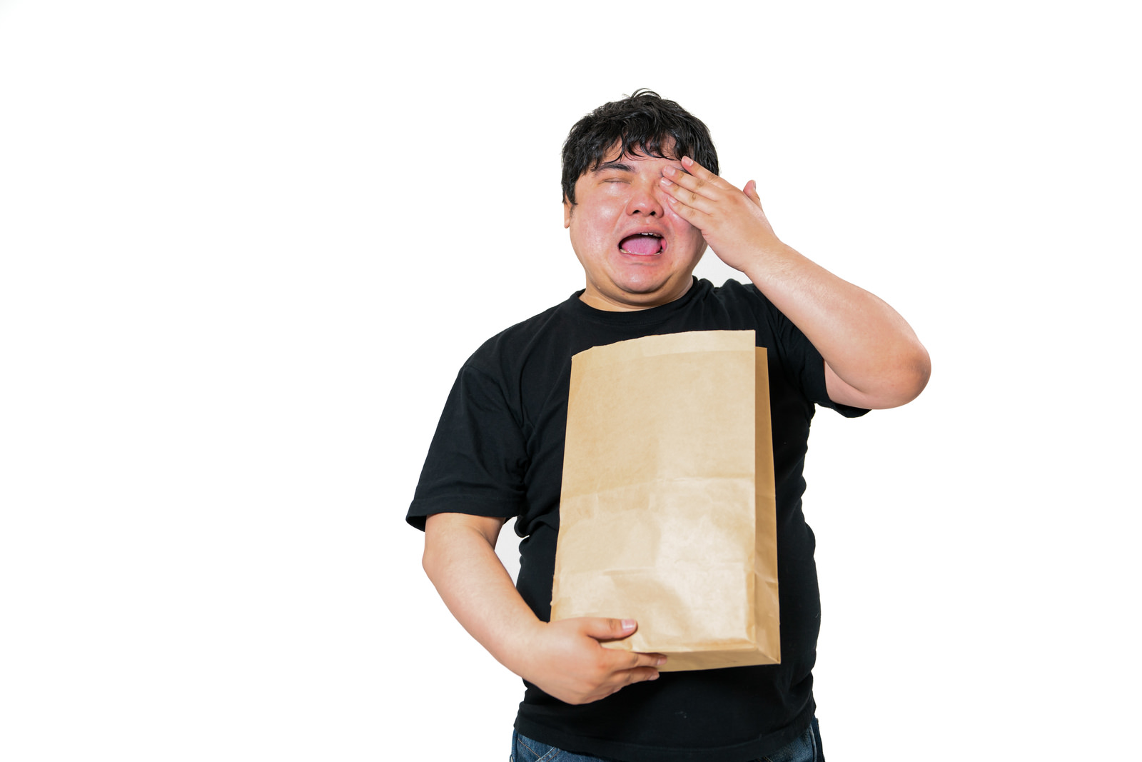 「左目を押えて泣く紙袋を持った男性 | フリー素材のぱくたそ」の写真［モデル：段田隼人］