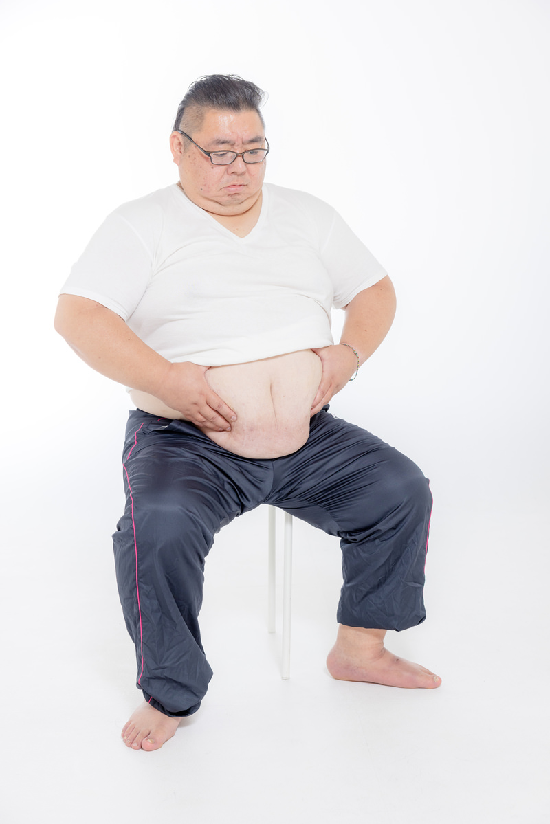 「お腹の肉を寄せる膨よかな男性 | フリー素材のぱくたそ」の写真［モデル：ダルマ親方］
