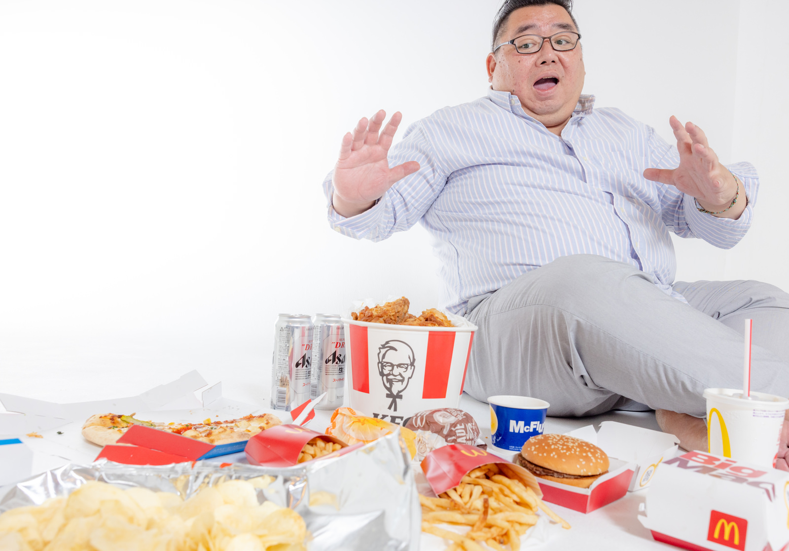 「フードデリバリーで届いた大量のフードを前に驚く太った男性 | フリー素材のぱくたそ」の写真［モデル：ダルマ親方］