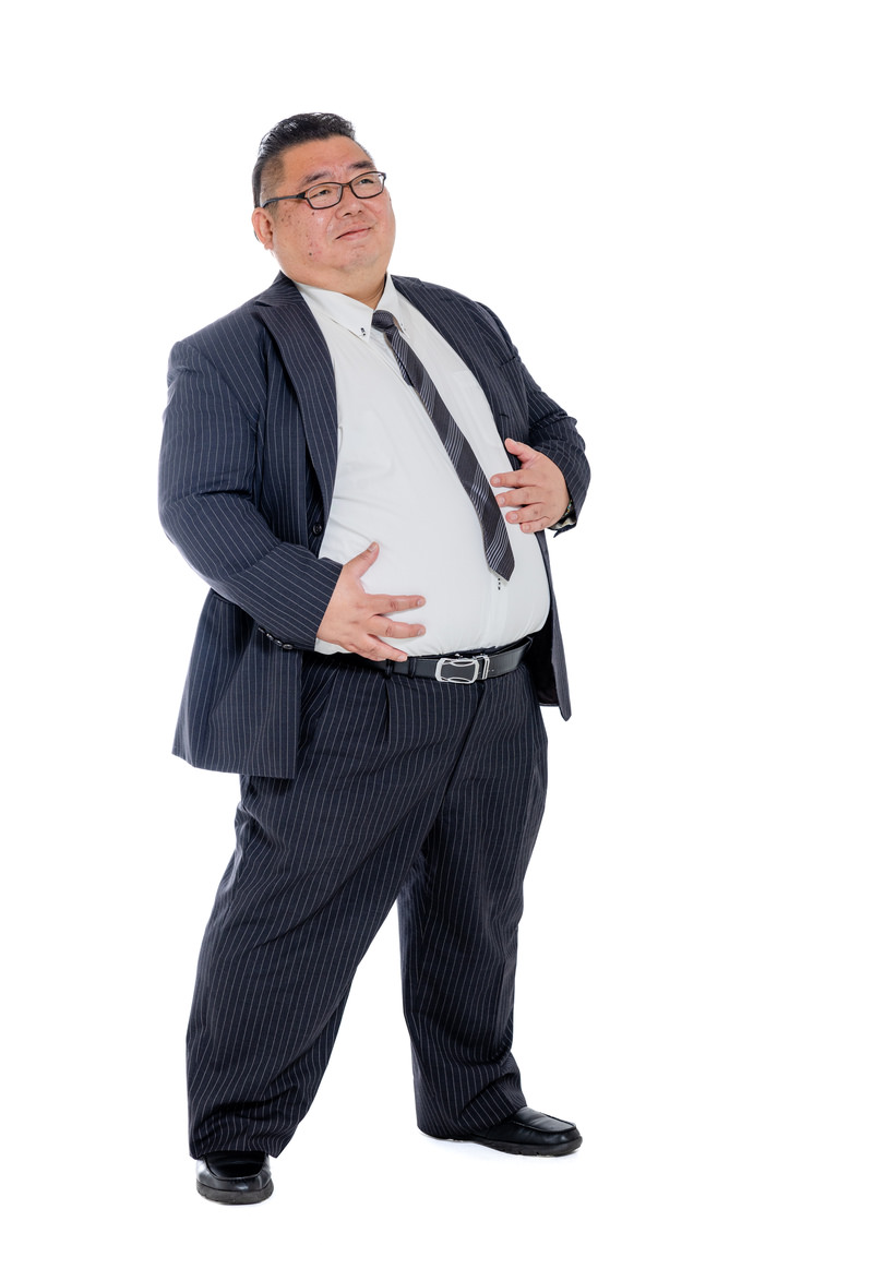 「お腹周りに付いた贅肉を気にするスーツ姿の男性 | フリー素材のぱくたそ」の写真［モデル：ダルマ親方］
