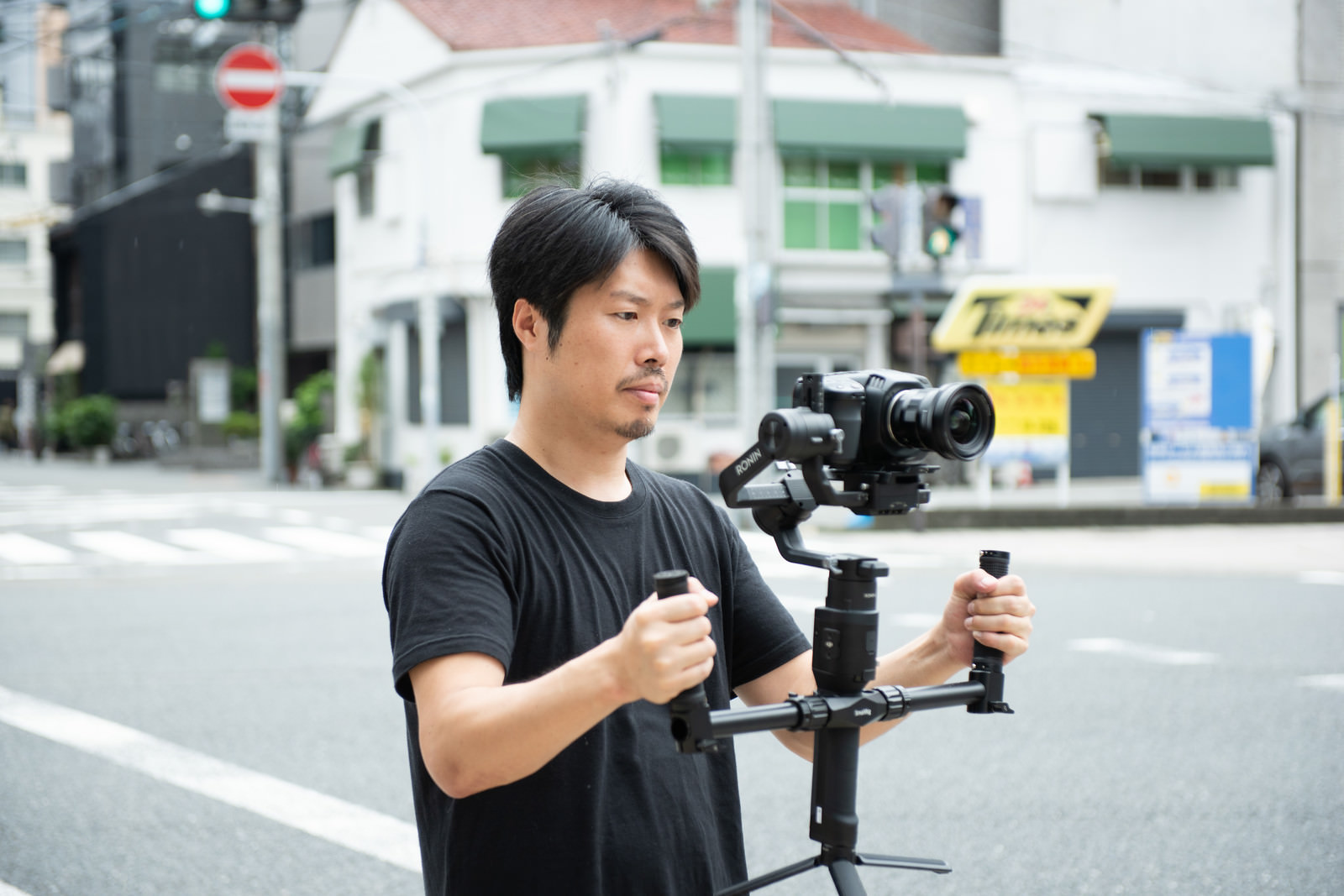 「屋外でジンバルを使った撮影をする男性カメラマン | フリー素材のぱくたそ」の写真［モデル：瀧野恵太］