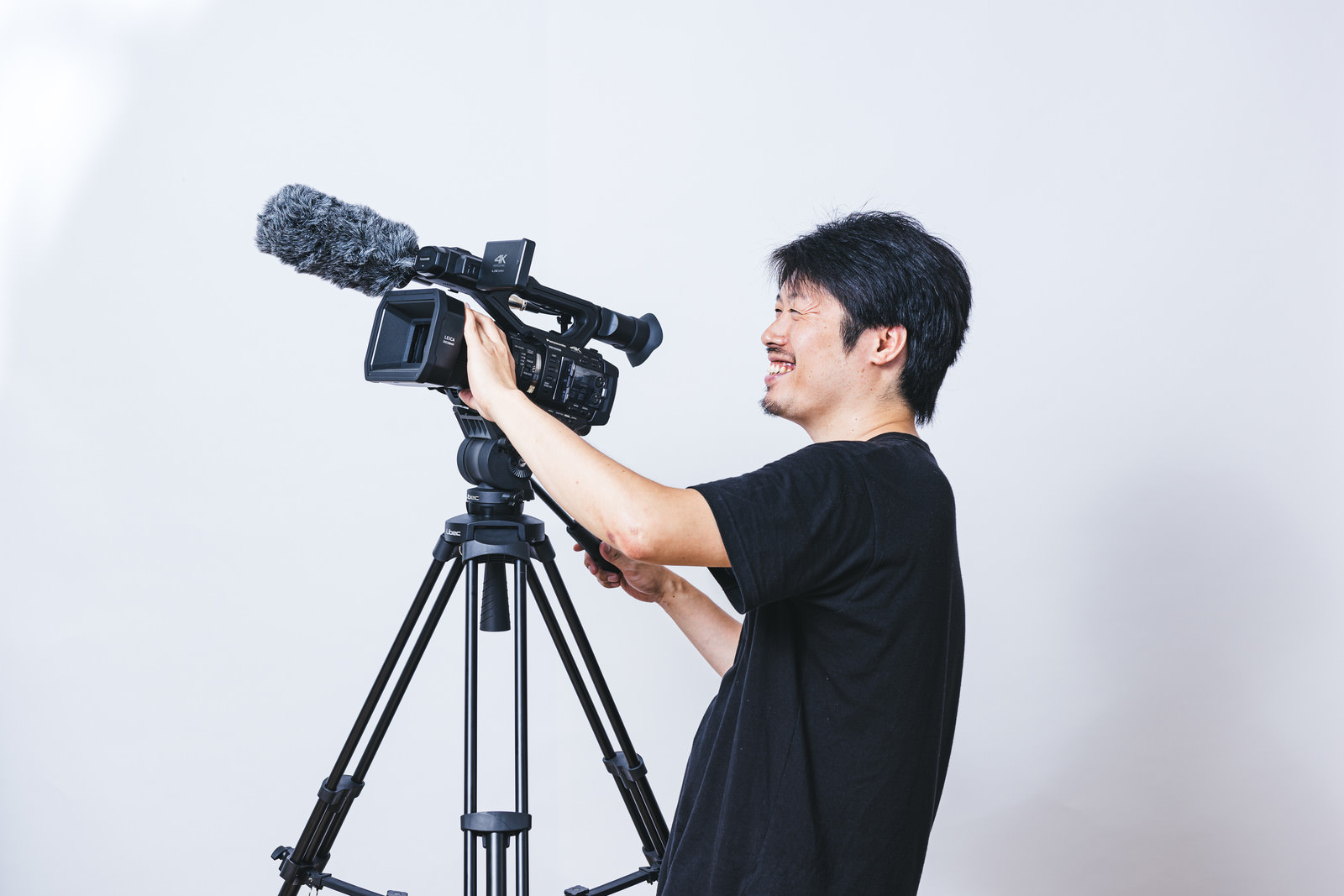 「笑顔で被写体を追うカメラマン | フリー素材のぱくたそ」の写真［モデル：瀧野恵太］