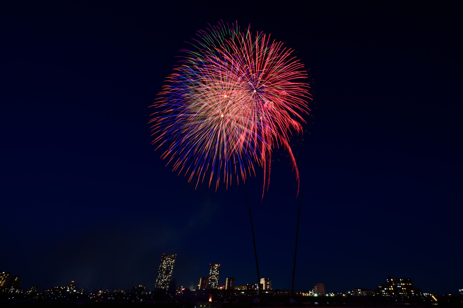 「都会の夜空に打ち上げる花火 | フリー素材のぱくたそ」の写真