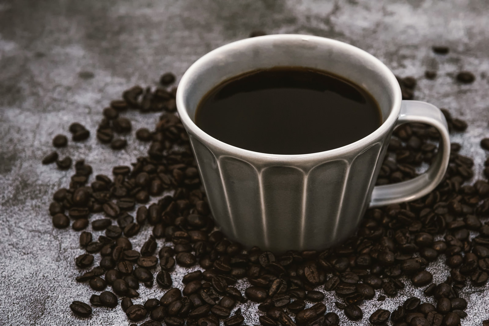 「焙煎珈琲豆と注がれたブラックコーヒー」の写真