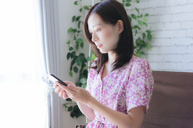 スマホを使って取引を行う女性の写真素材 ぱくたそ