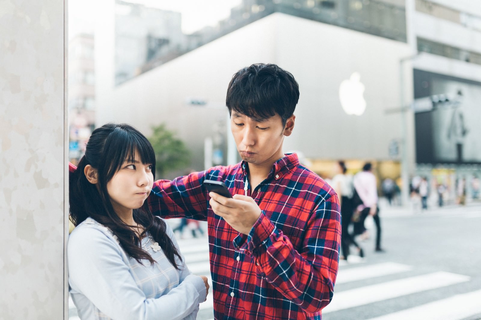 「デートの待ち合わせに遅刻し憤怒する彼女とスマホばかりを気にする彼氏」の写真［モデル：大川竜弥 Lala］