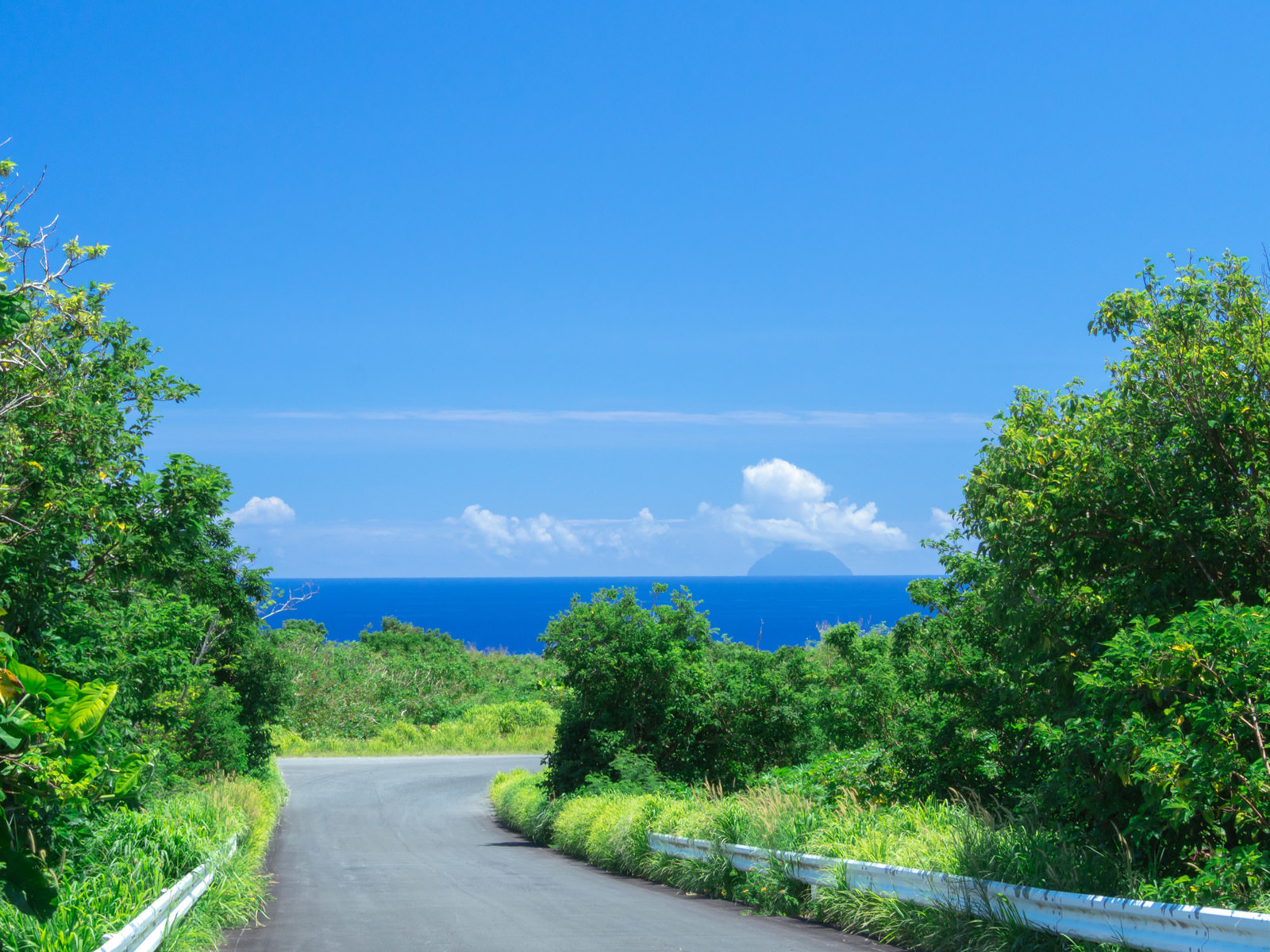 坂道の先に広がる蒼海と奥にかすんで見える南硫黄島の写真素材 - ぱくたそ