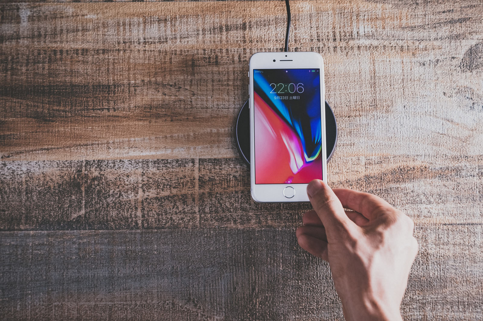 「iPhone 8 をワイヤレス充電パッドにかざす | フリー素材のぱくたそ」の写真