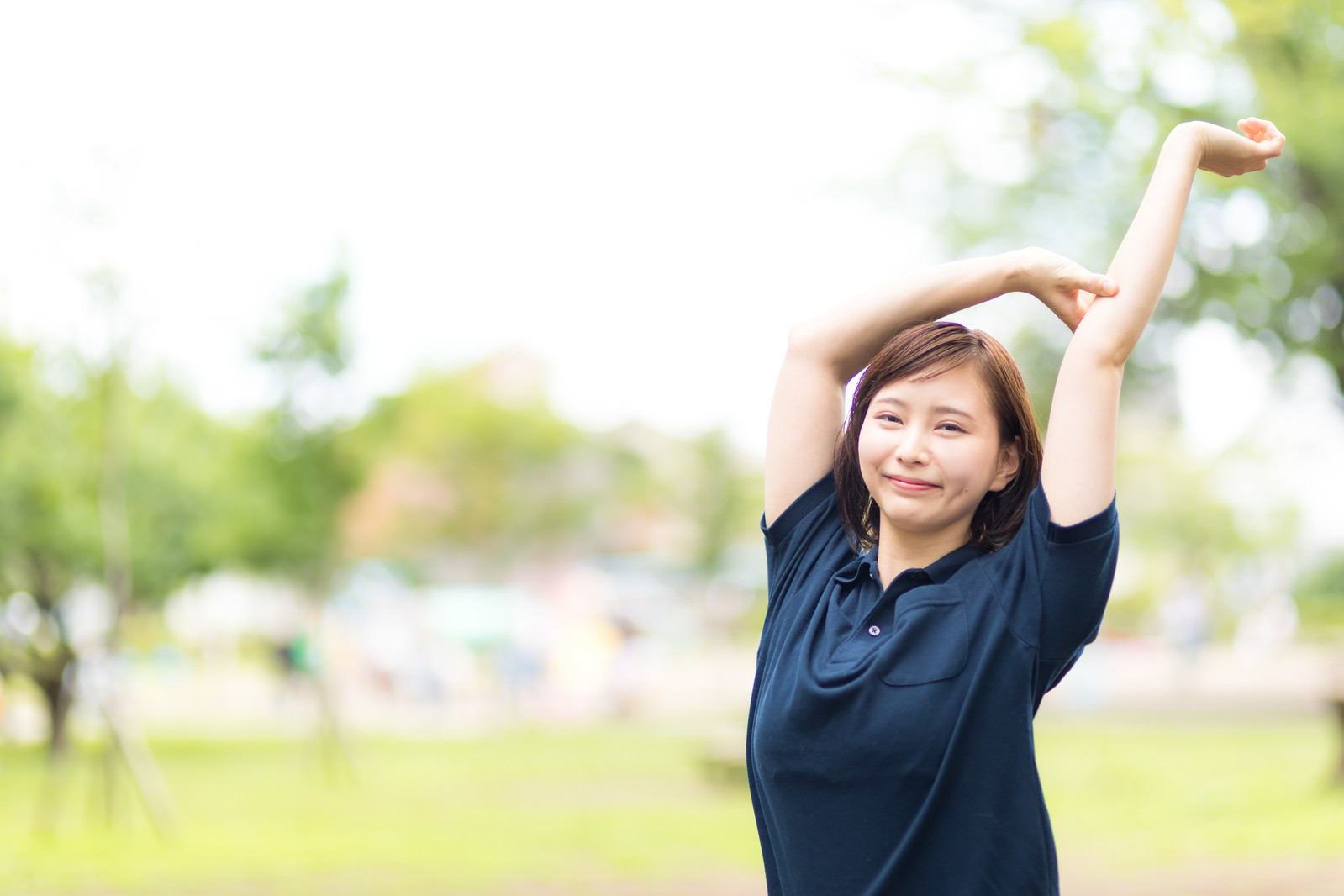 「公園で伸びをする女性 | フリー素材のぱくたそ」の写真［モデル：yumiko］