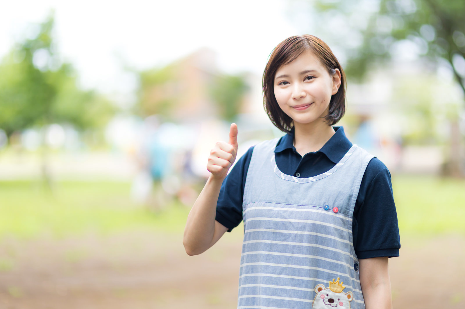 「エプロン姿でいいねする女性（屋外） | フリー素材のぱくたそ」の写真［モデル：yumiko］