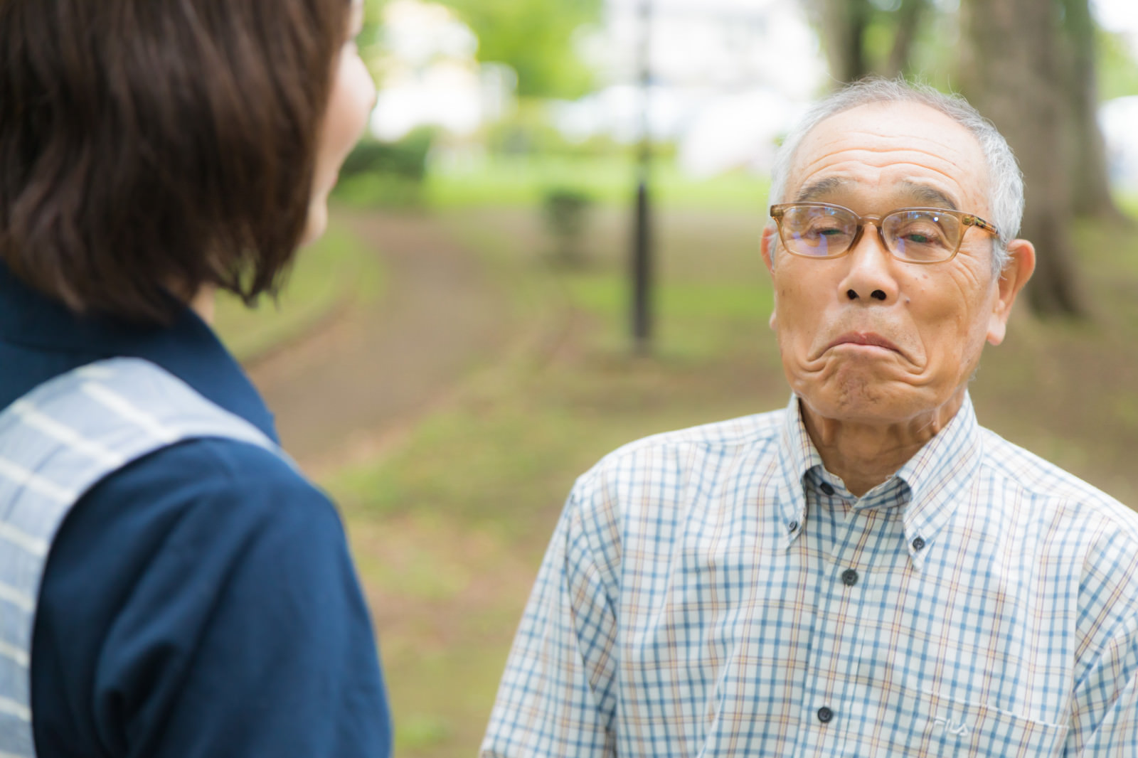 口をへの字にして動かない高齢者と説得するヘルパー｜フリー素材のぱくたそ