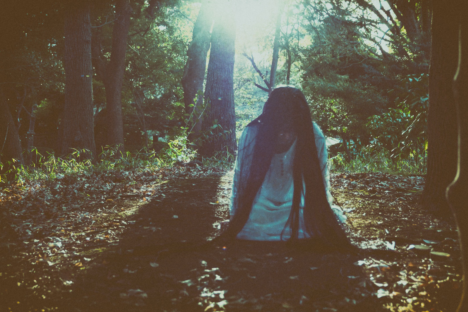 「森の中で蹲りながら近づいてくる女性」の写真［モデル：緋真煉］