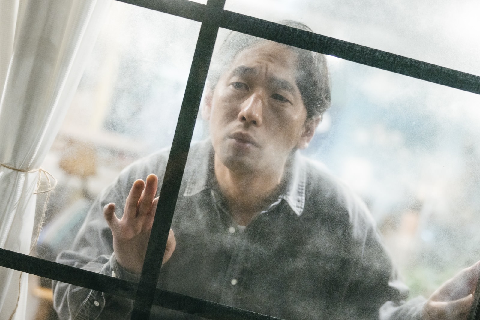 「窓ガラスから張り込みする探偵」の写真［モデル：大川竜弥］