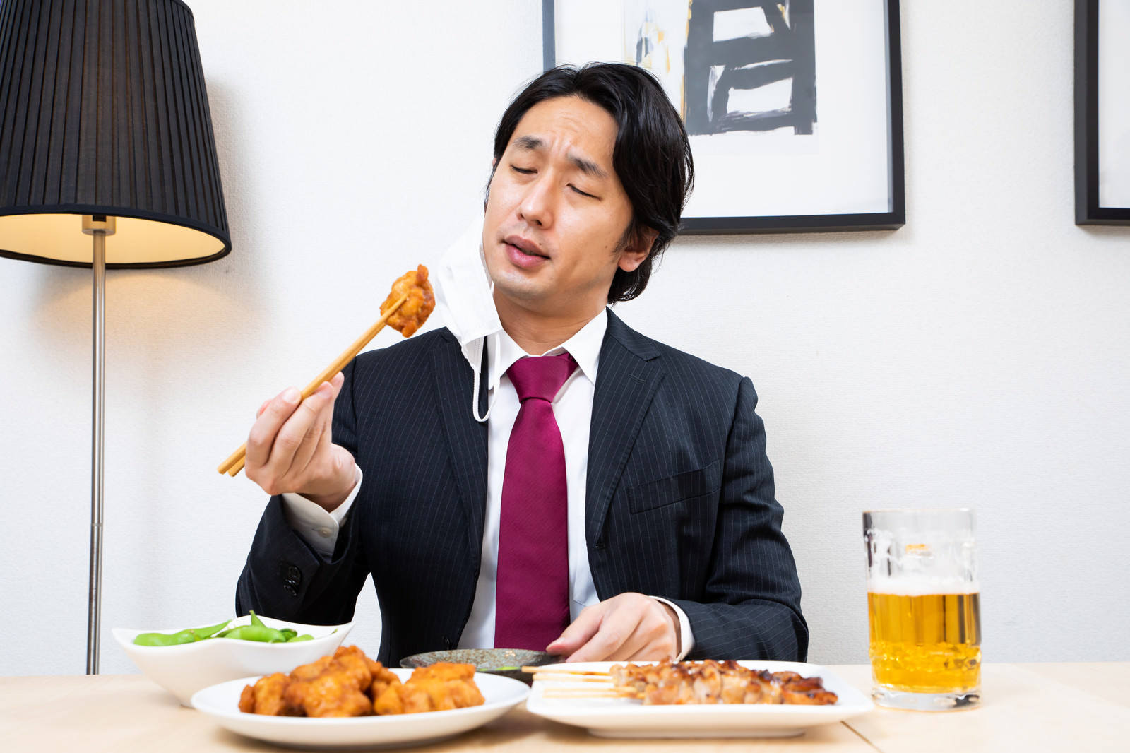 「唐揚げに舌鼓を打つ会社員 | フリー素材のぱくたそ」の写真［モデル：大川竜弥］