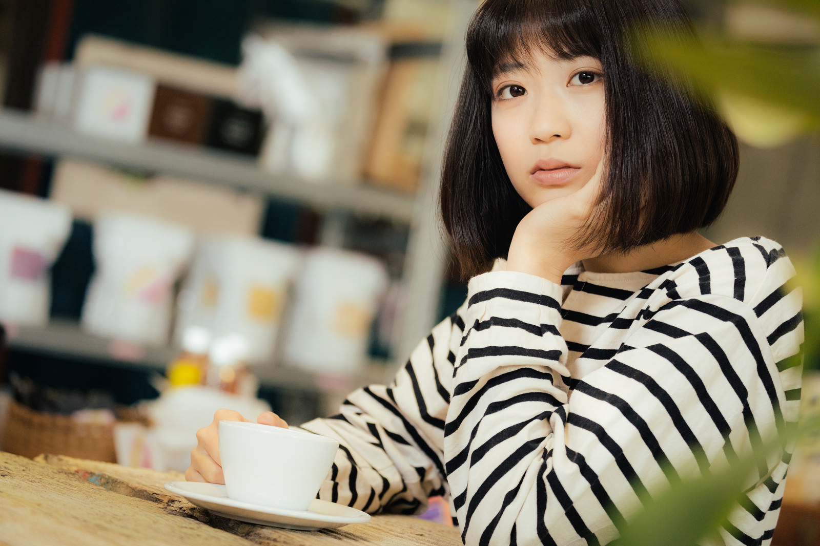 「カフェで退屈そうにこちらを見つめる女性」の写真［モデル：塩田みう］