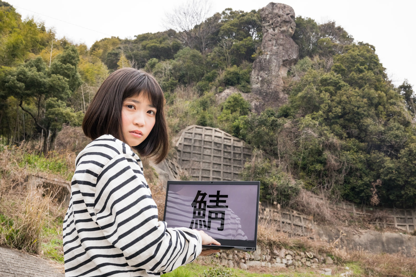 「鯖くさらかし岩の近くでサーバーにアクセスする女性」の写真［モデル：塩田みう］