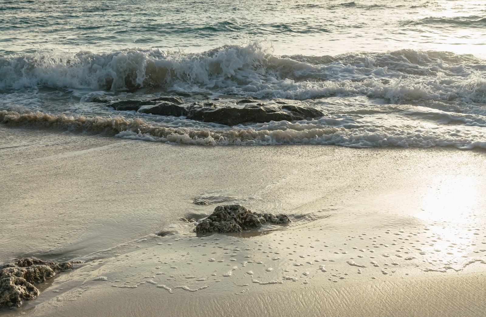 「砂浜に残る泡 | フリー素材のぱくたそ」の写真