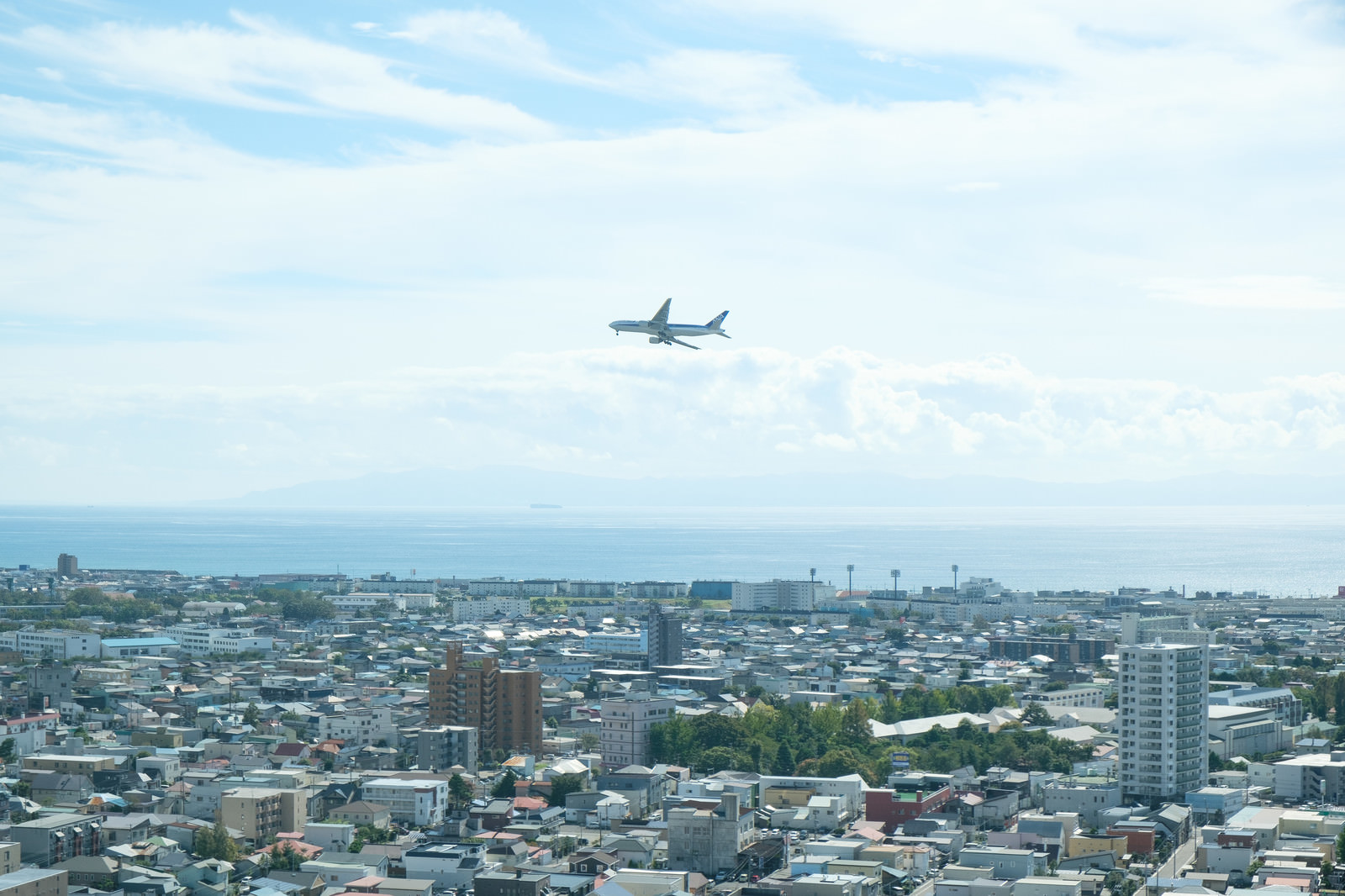 「市街地の上空を旋回する旅客機 | フリー素材のぱくたそ」の写真