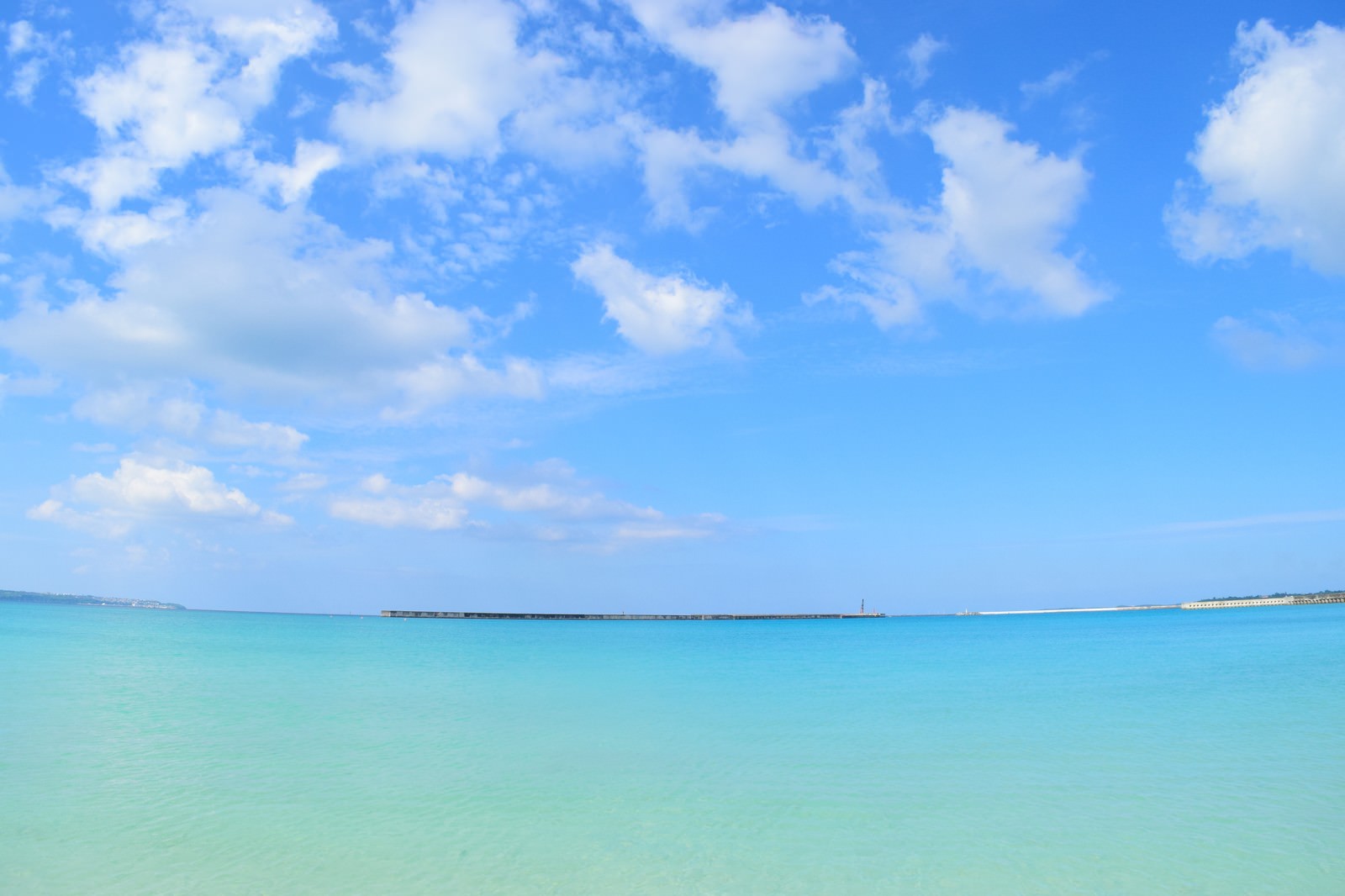 沖縄の海と遠くに見える防波堤の写真を無料ダウンロード フリー素材 ぱくたそ
