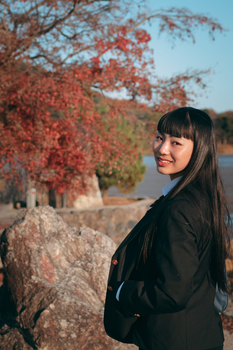 「紅葉と後ろを振り返る女性 | フリー素材のぱくたそ」の写真［モデル：なんこ］