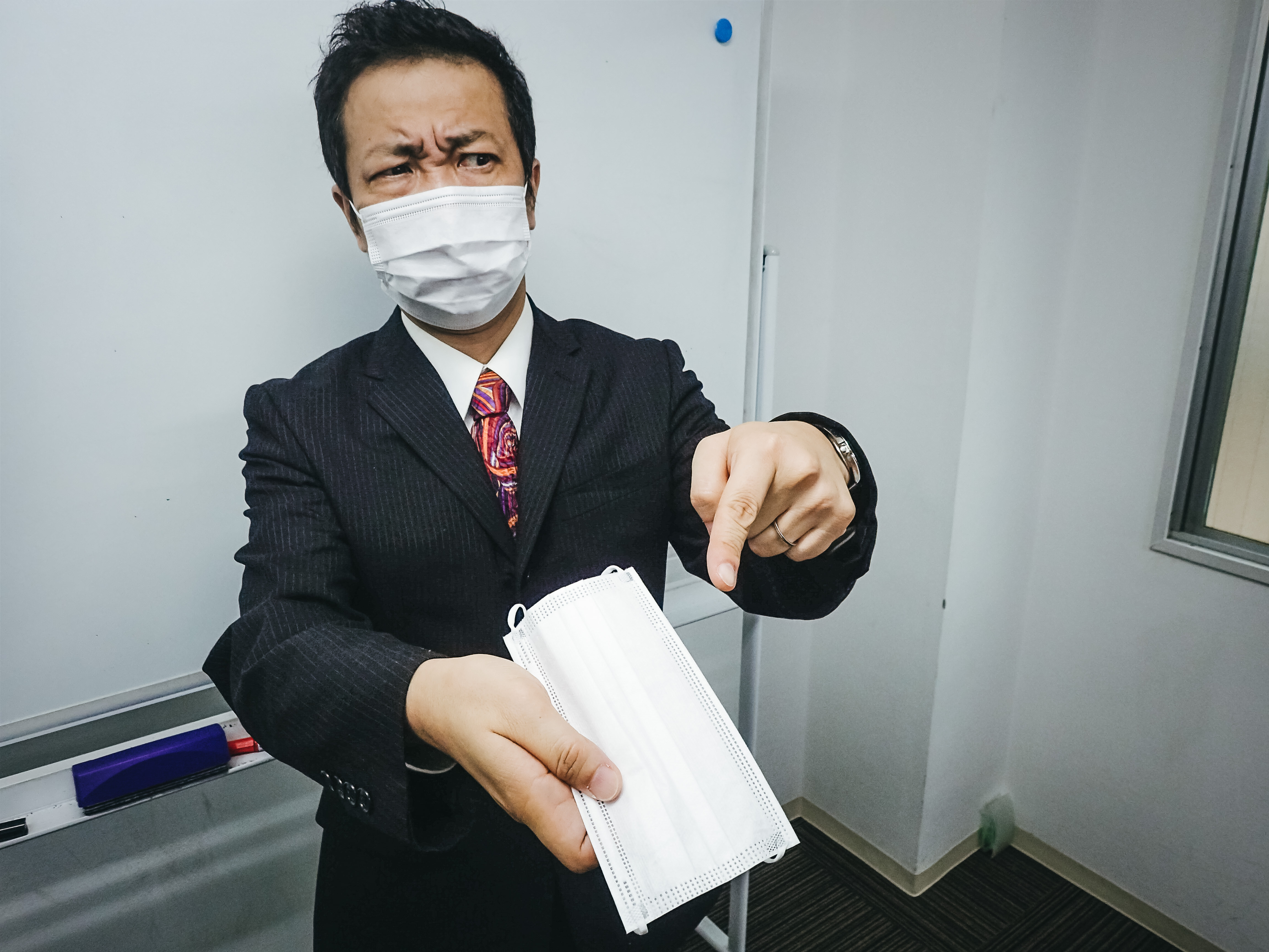 嫌な顔をしながらマスクを手渡しする会社員の写真素材 ぱくたそ