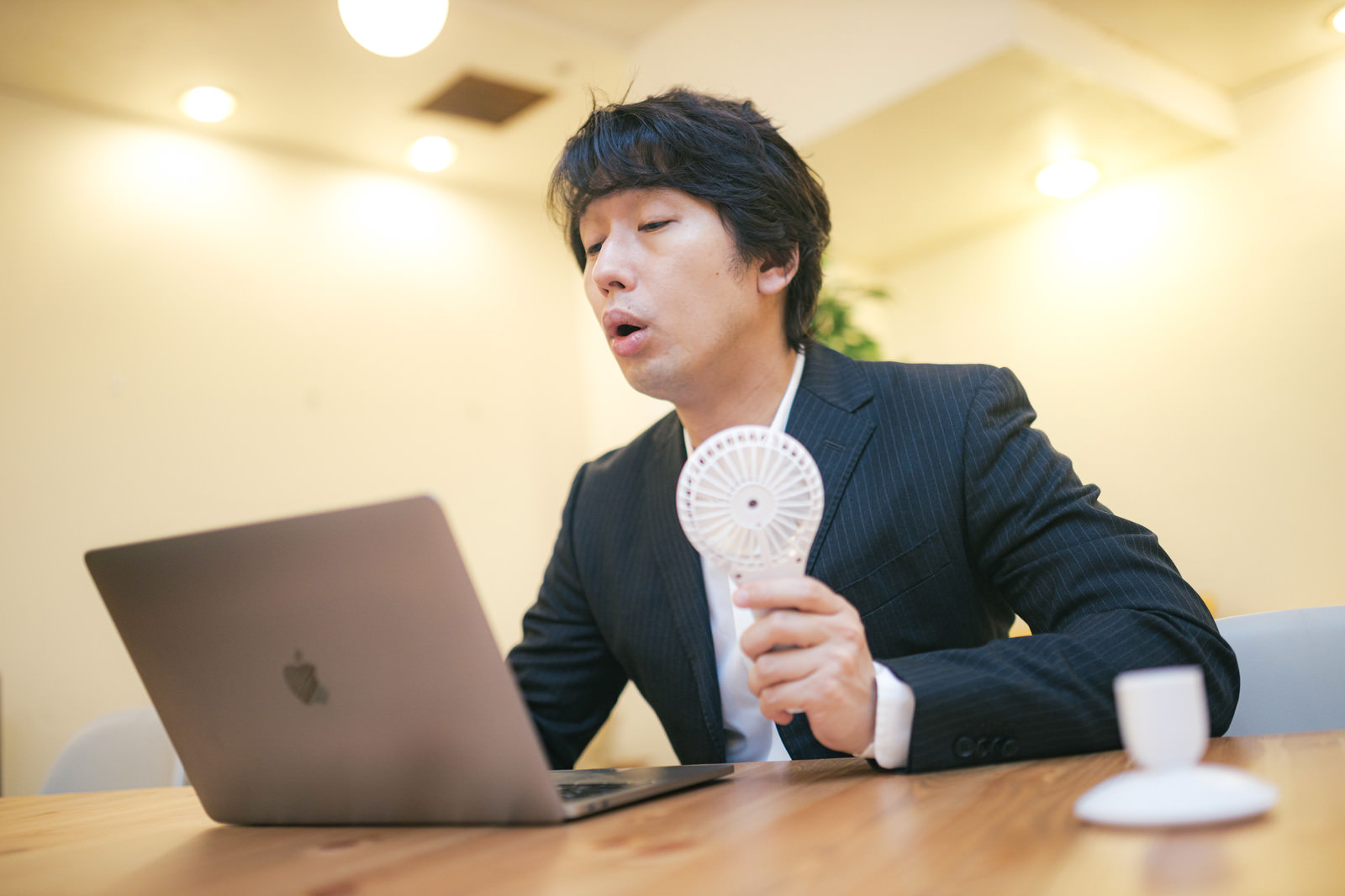 「オンライン会議中にハンディ扇風機を使用する男性」の写真［モデル：大川竜弥］