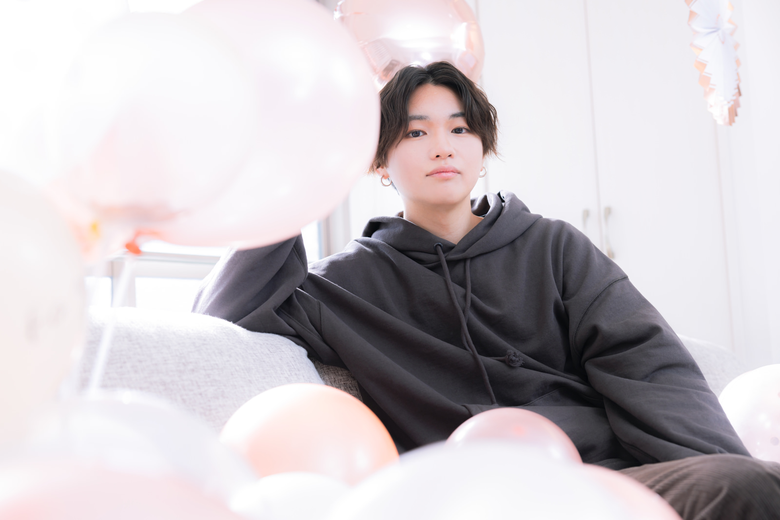 「パーティー用バルーンに囲まれる推しの男性 | フリー素材のぱくたそ」の写真［モデル：SHUN］