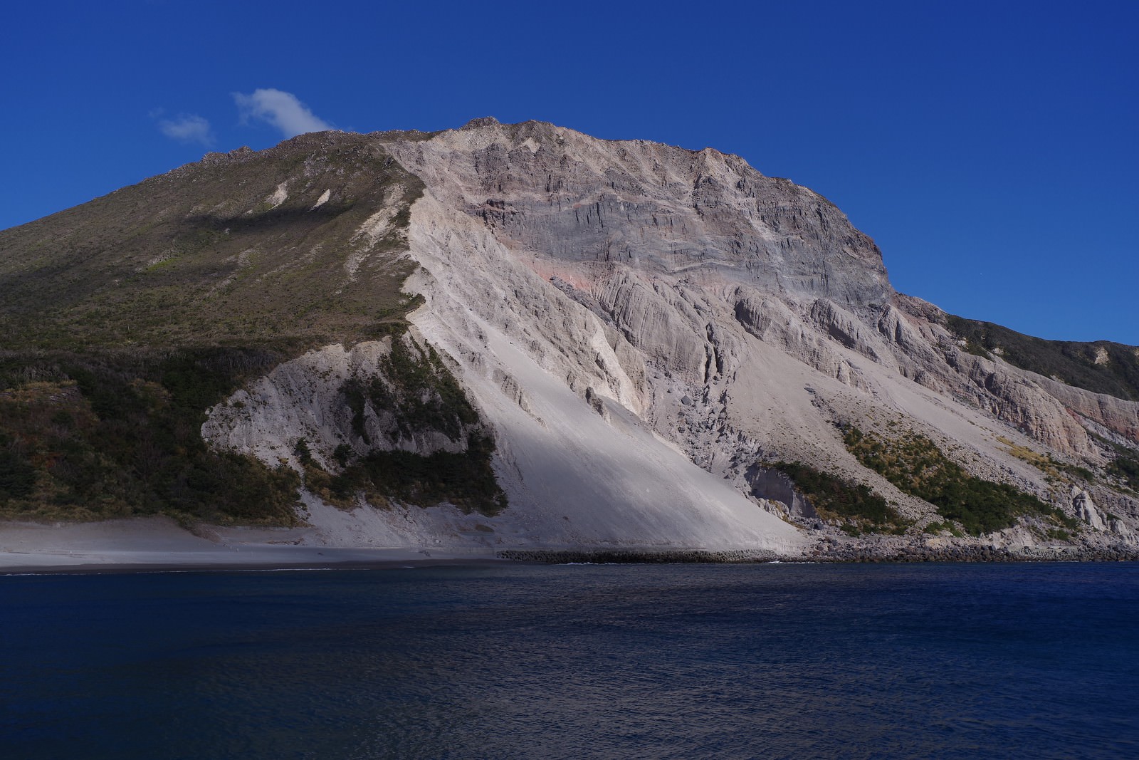 「神津島の多幸湾から見える斜面が崩れた山 | フリー素材のぱくたそ」の写真
