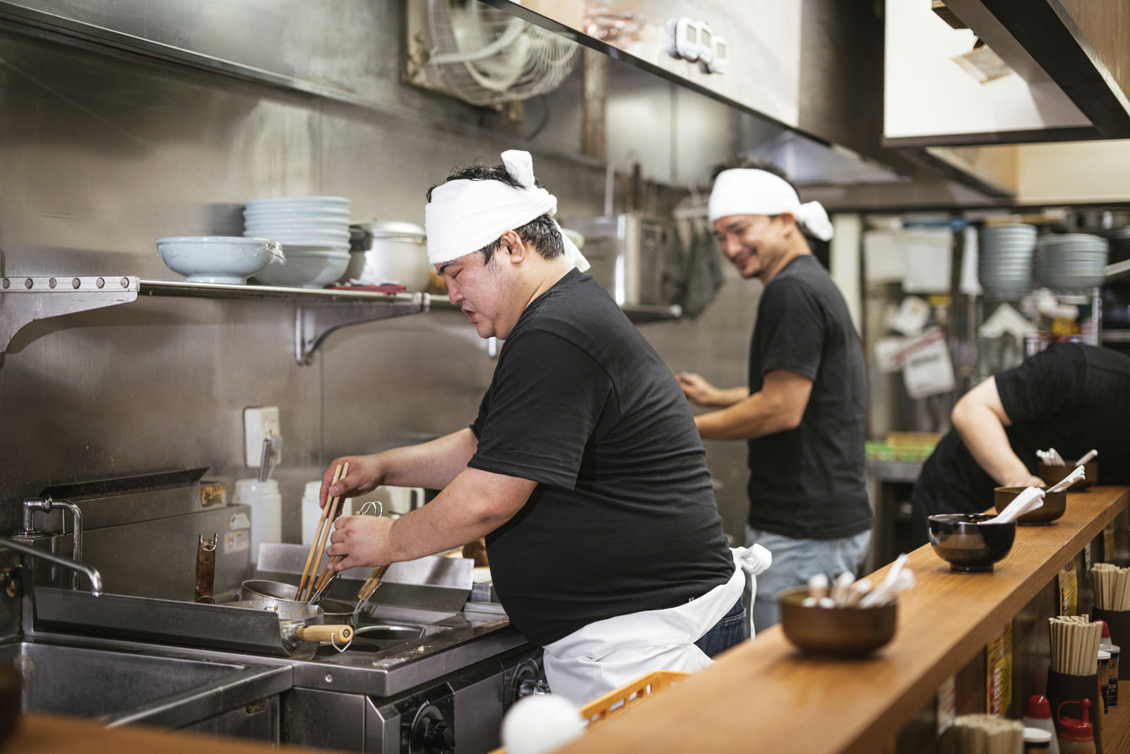 「厨房に立つ割腹のいいラーメン店主 | フリー素材のぱくたそ」の写真［モデル：段田隼人 Max_Ezaki 大川竜弥］
