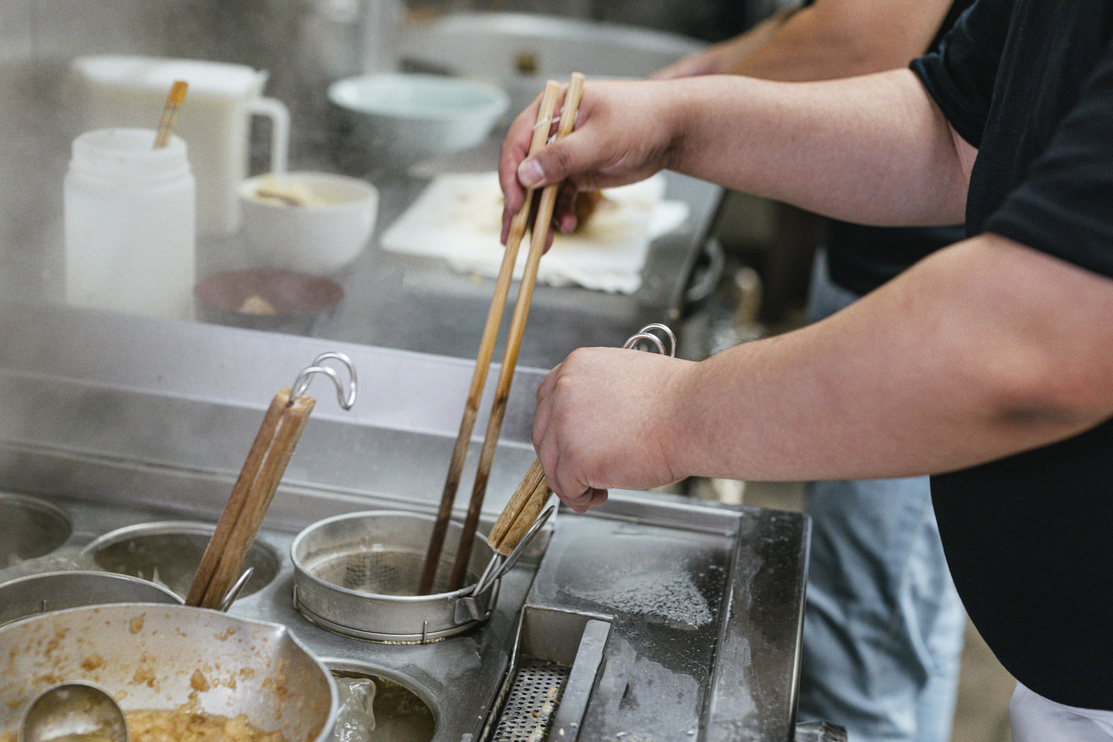 「麺が固まらないようにテボに箸を入れる様子」の写真