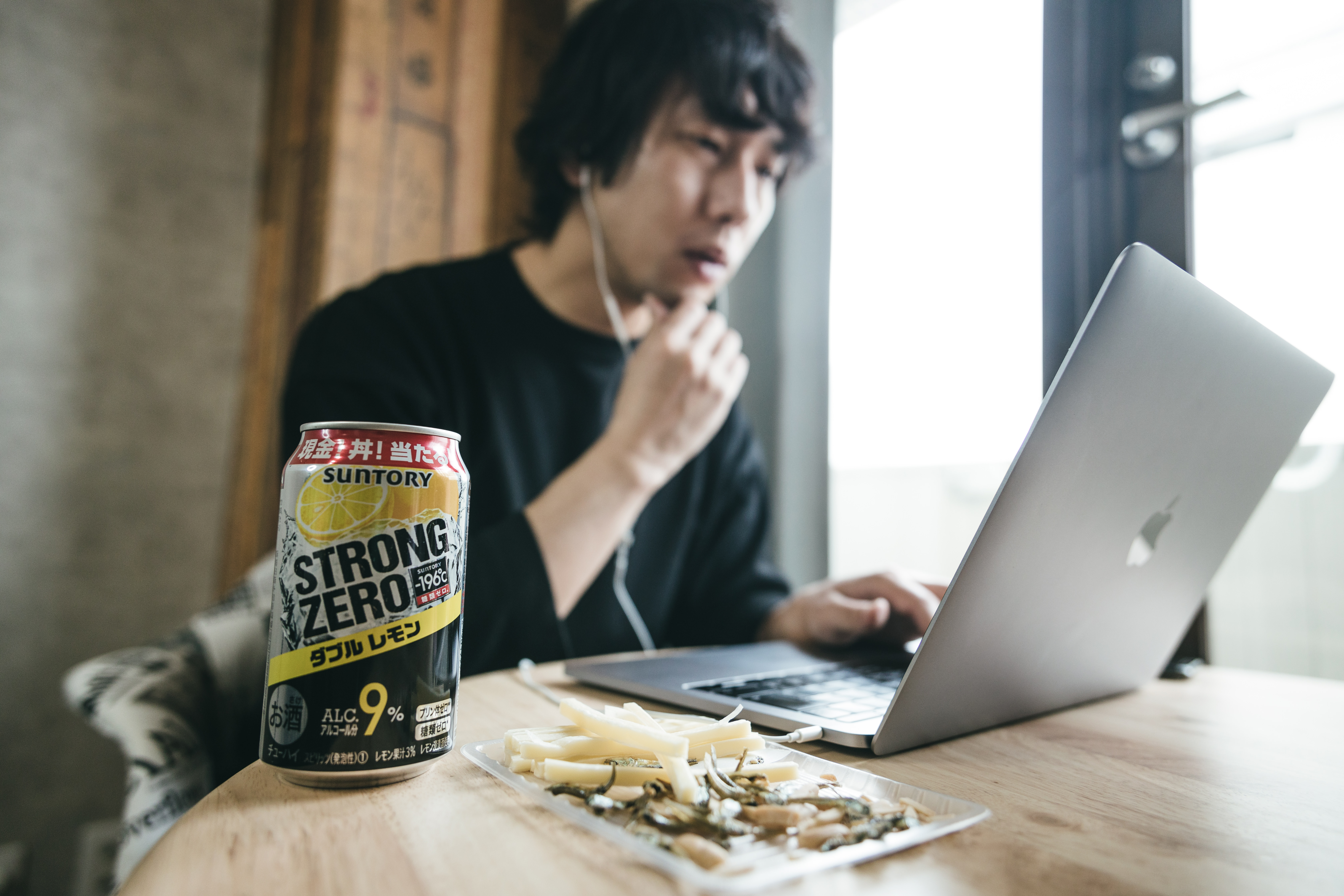 リモートワーク中のデスクに置かれたお酒とおつまみの写真素材 ぱくたそ