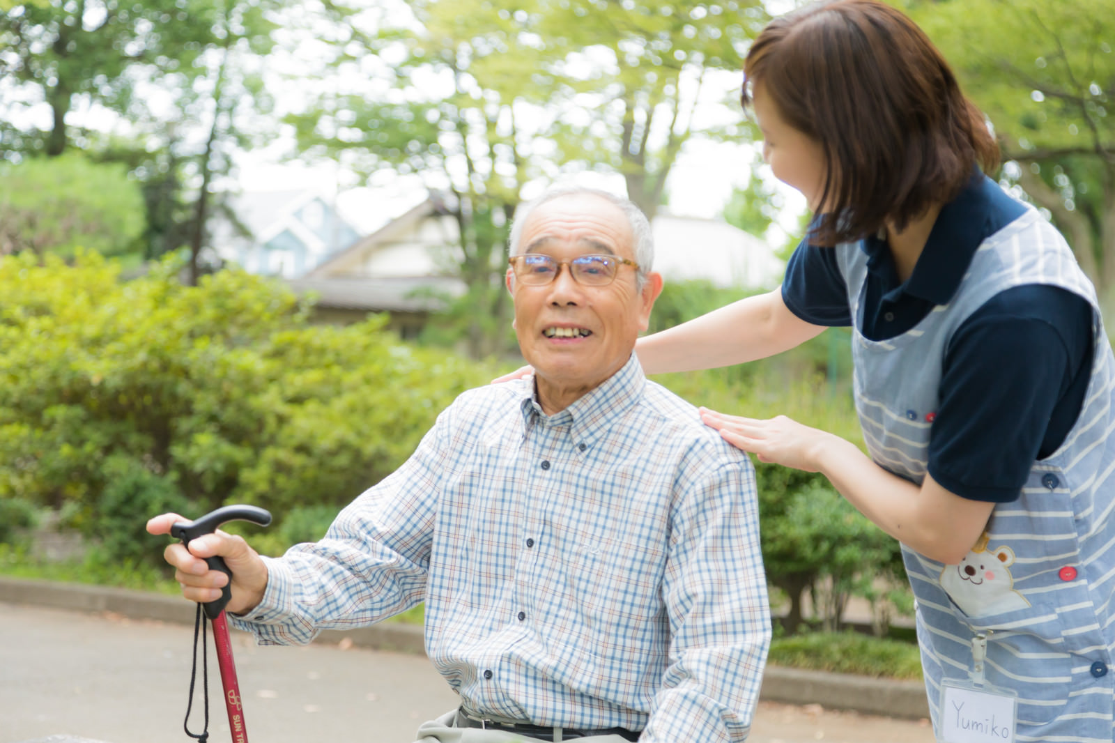 「公園で日光浴を楽しむおじいさんと介護士の女性」の写真［モデル：まーちゃん yumiko］