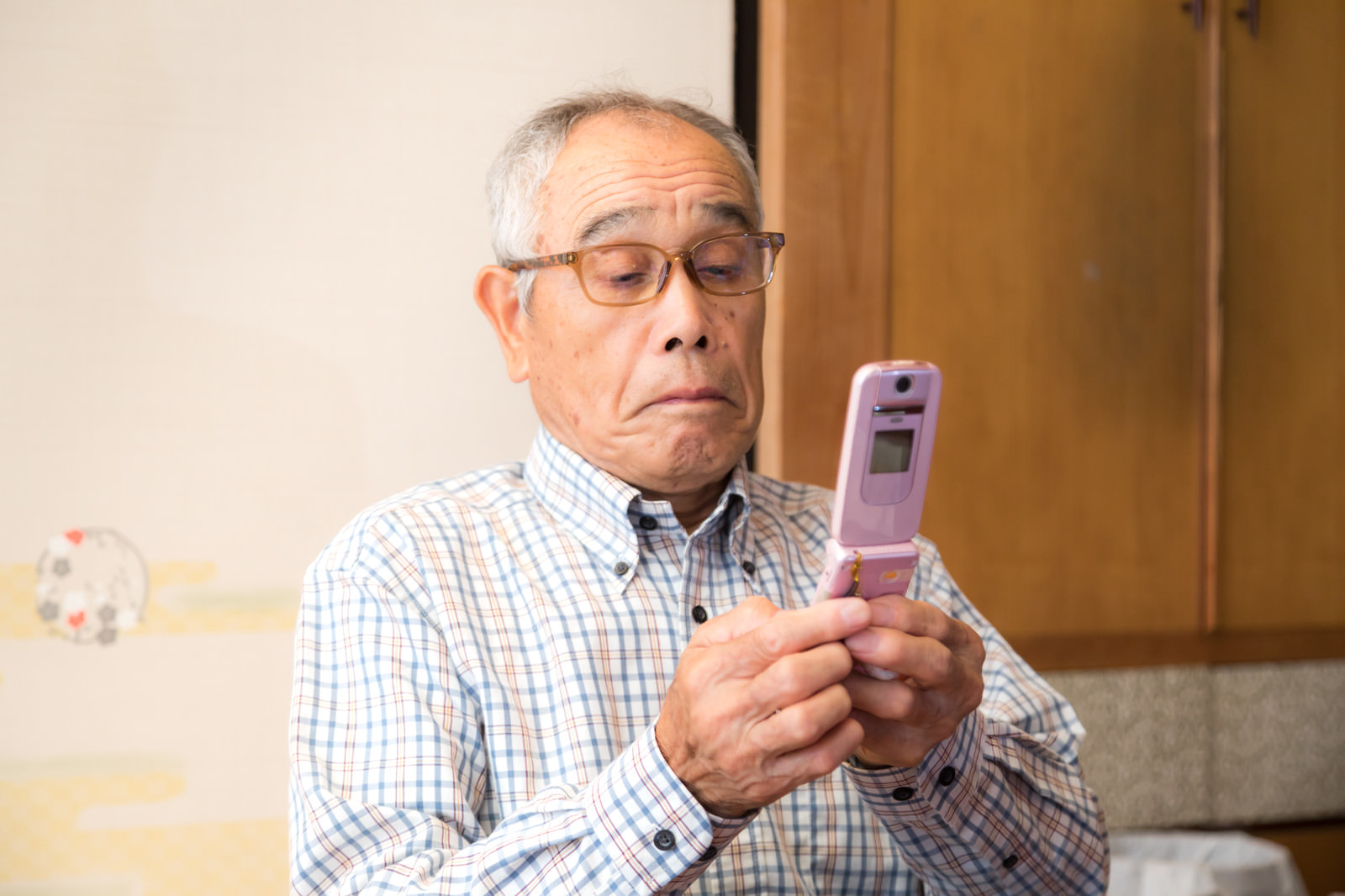 「覚えたての携帯電話を使うお爺さん」の写真［モデル：まーちゃん］