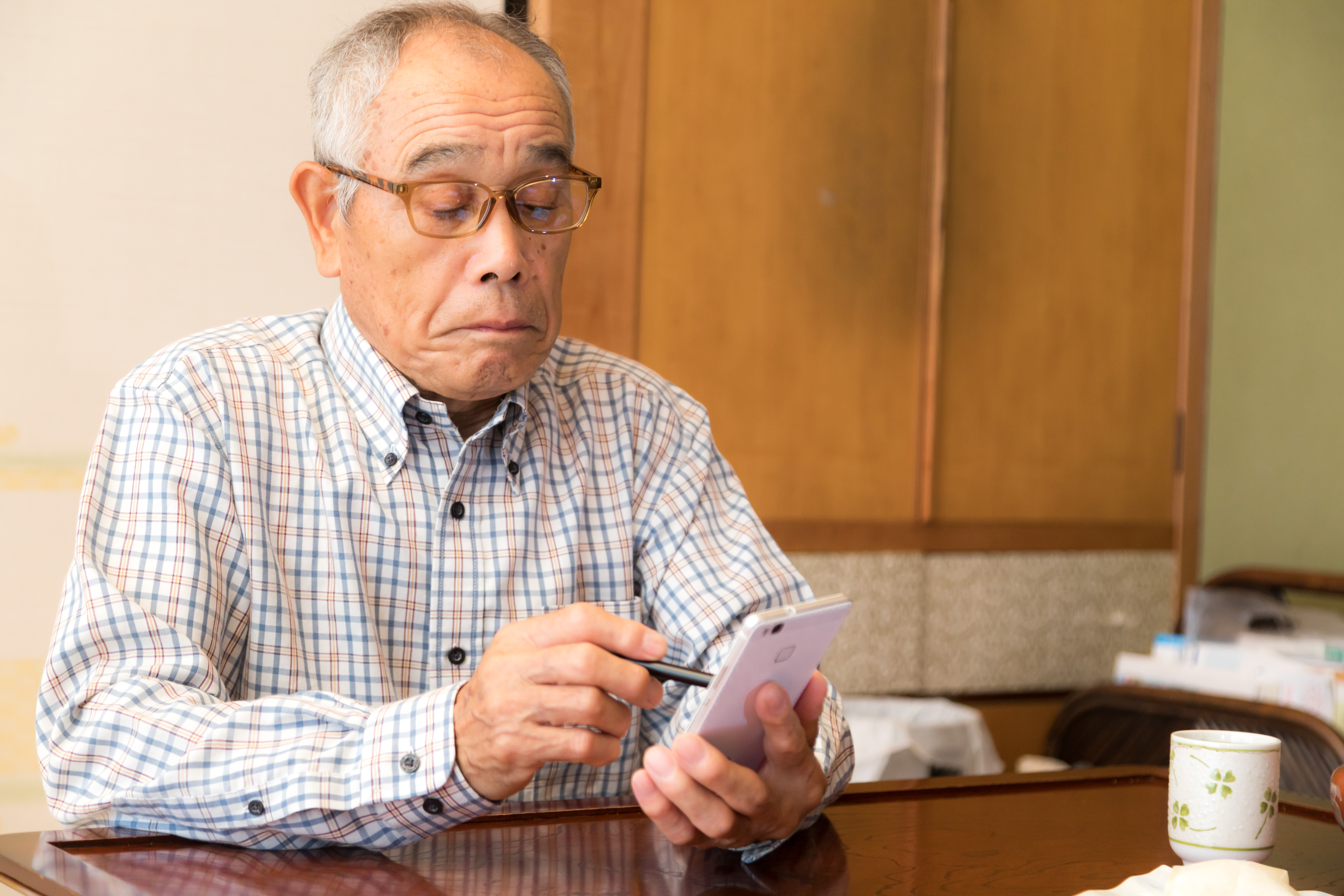 慣れない手つきでスマホを弄る高齢のお爺さんの写真を無料ダウンロード フリー素材 ぱくたそ