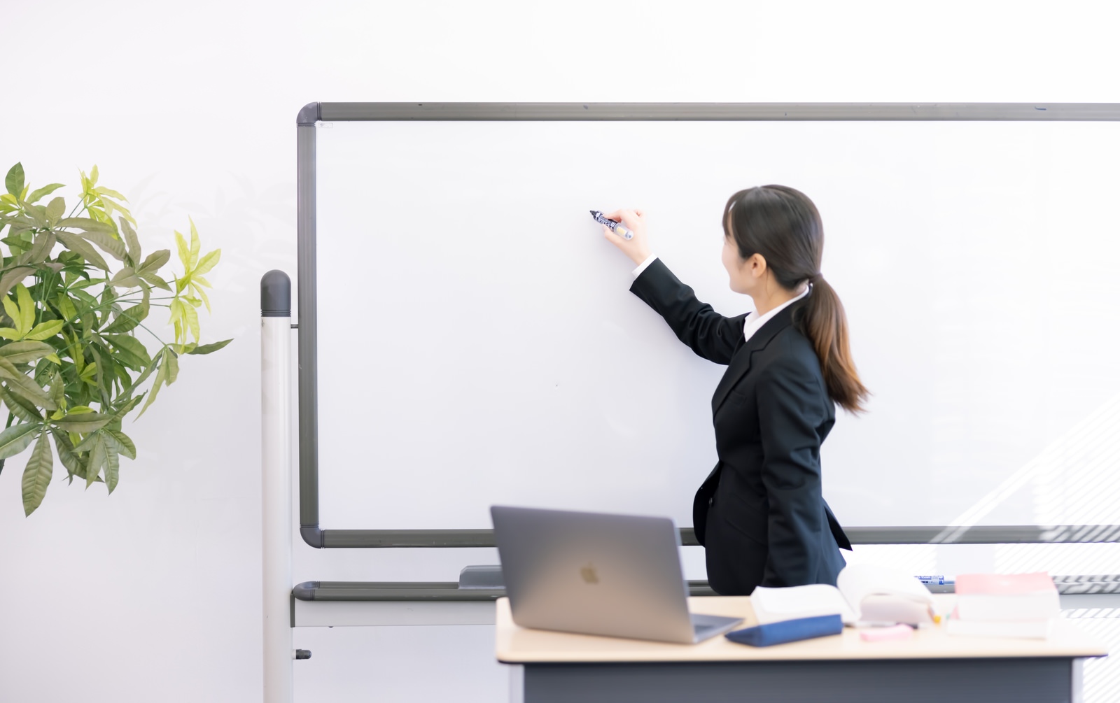 「ホワイトボードに書き込む女性講師 | フリー素材のぱくたそ」の写真［モデル：SAKI］