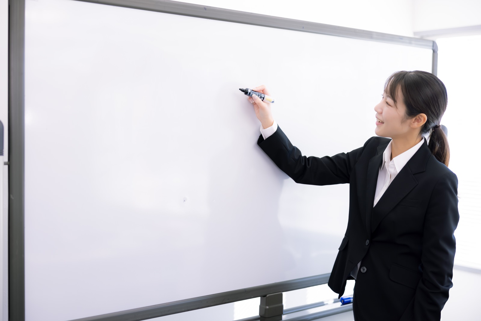 「笑顔で説明する女性講師 | フリー素材のぱくたそ」の写真［モデル：SAKI］