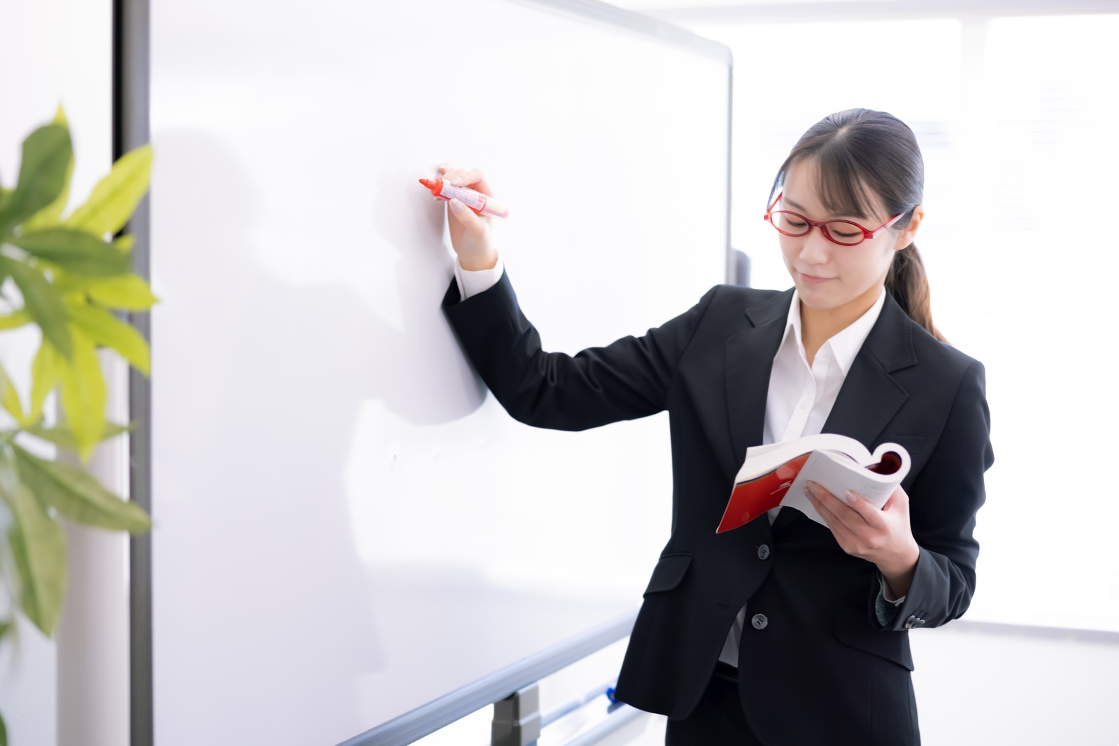 「ホワイトボードで授業をする女子講師 | フリー素材のぱくたそ」の写真［モデル：SAKI］