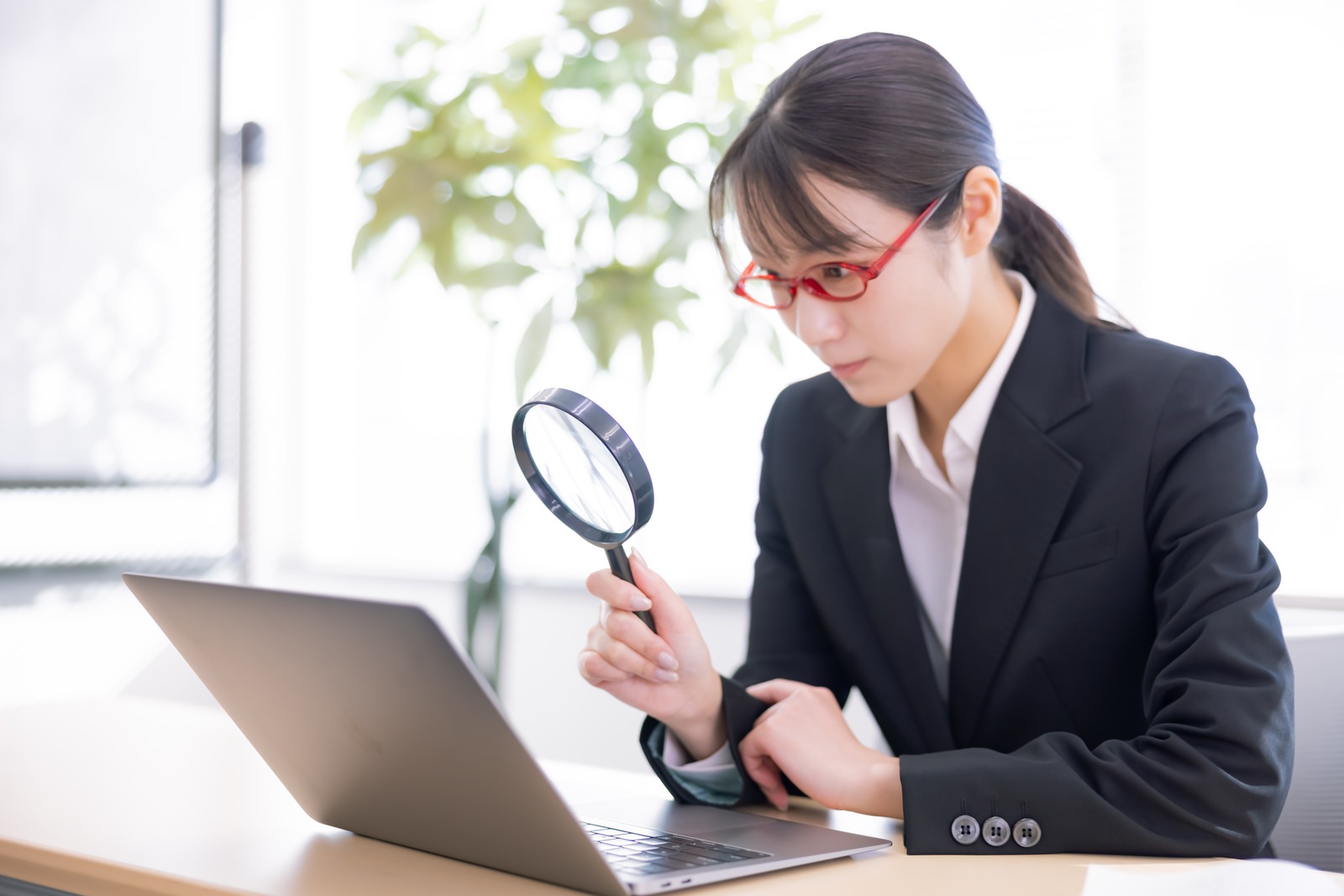 「拡大鏡を使ってチェックする女性社員 | フリー素材のぱくたそ」の写真［モデル：SAKI］