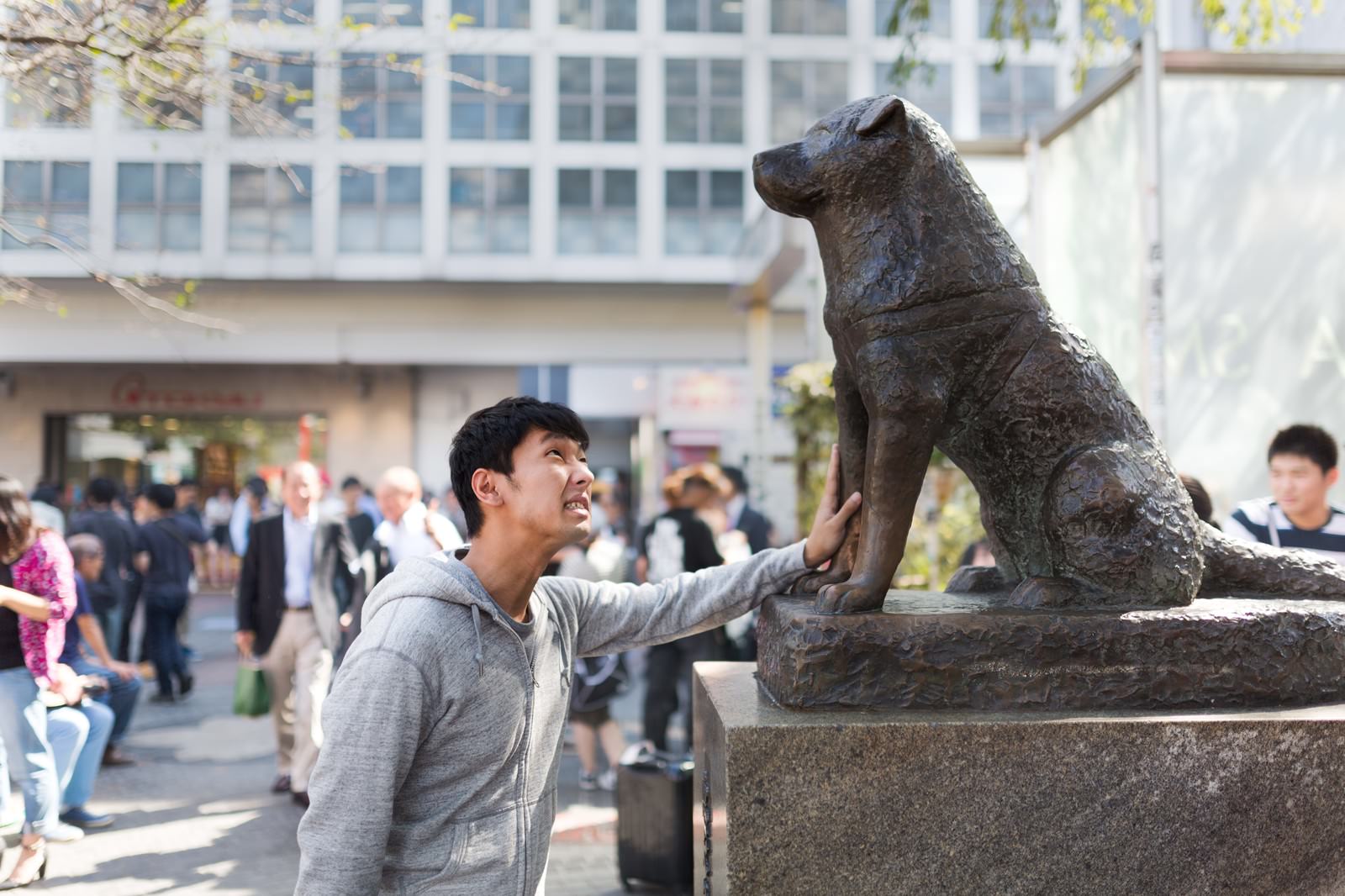 「女性を口説けず犬の銅像に慰めてもらうナンパ師」の写真［モデル：大川竜弥］