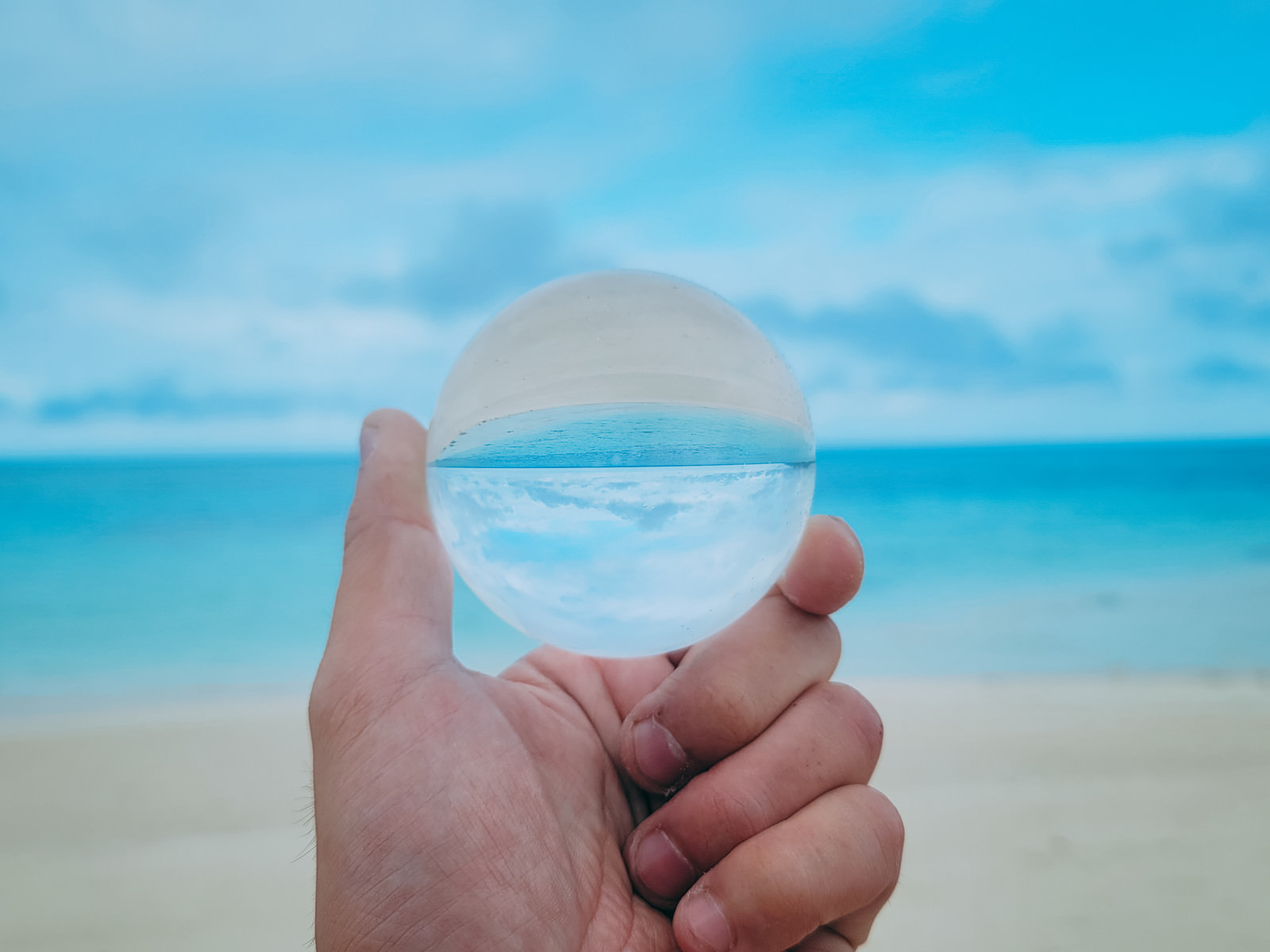 「水晶玉から覗く南国の砂浜 | フリー素材のぱくたそ」の写真
