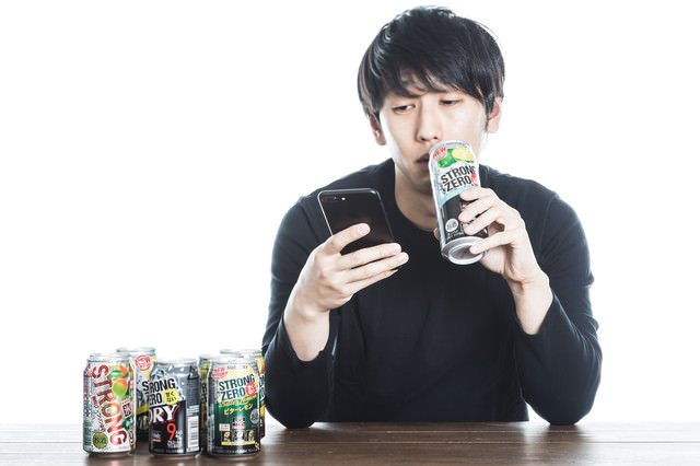 「缶チューハイを飲みながら廃課金するソシャゲユーザー」のフリー写真素材