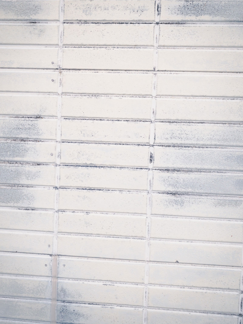 「擦れ跡残るホワイト色のタイル壁（テクスチャ） | フリー素材のぱくたそ」の写真