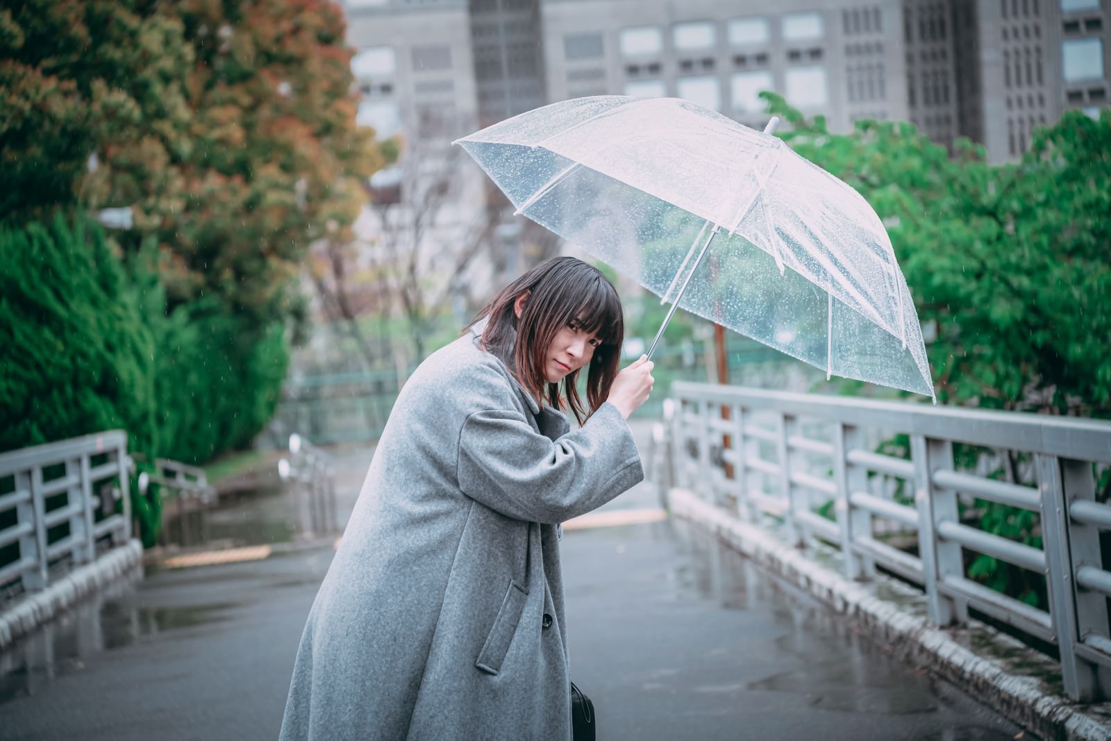 「ビニール傘を差して辺りを警戒する女性 | フリー素材のぱくたそ」の写真［モデル：たけべともこ］